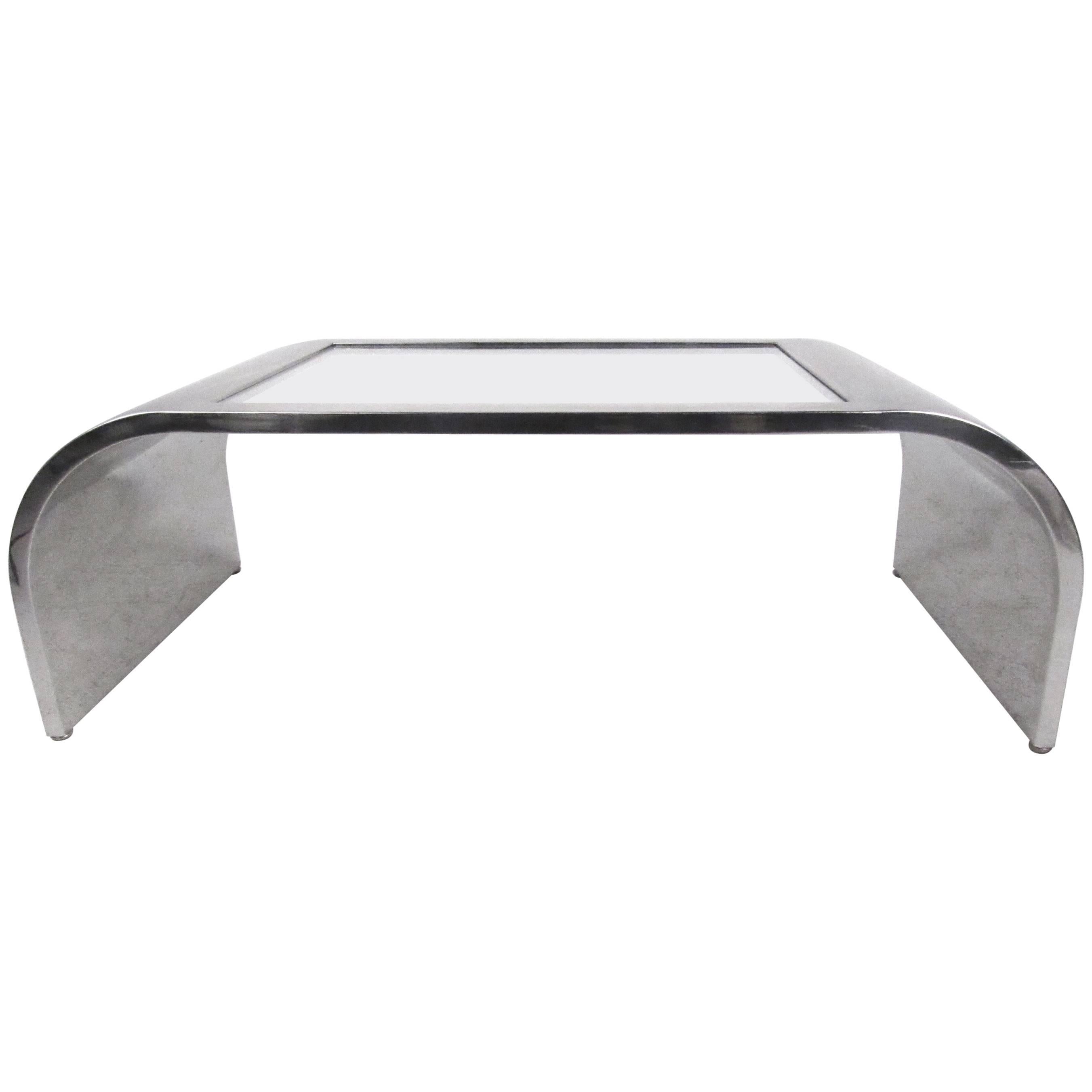 This stainless steel and glass coffee table features a stylish waterfall design with sculptural curved edges, and unique Spage Age modern appeal. Perfect coffee table for any interior, please confirm item location (NY or NJ).