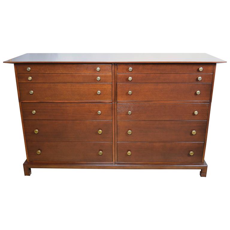 C. G. Kimerly in the Gibbings style 1940s Widdicomb modular 12 drawer mahogany dresser with circular brass pulls.
Four separate three drawer cases fasten together resting on a common base topped by an overhanging top.
Each of the four cases has an