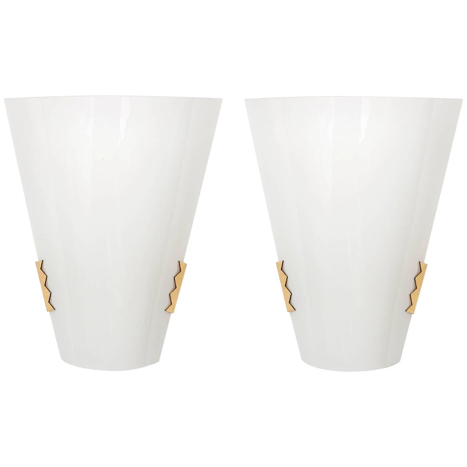 A set of three polished brass and white opaline glass wall lamps by J.T. Kalmar, Austria, manufactured in Mid-Century, circa 1970.
A brass mounting fixture holds a bent opal glass.
Each light takes one medium base Edison bulb.

The price is per