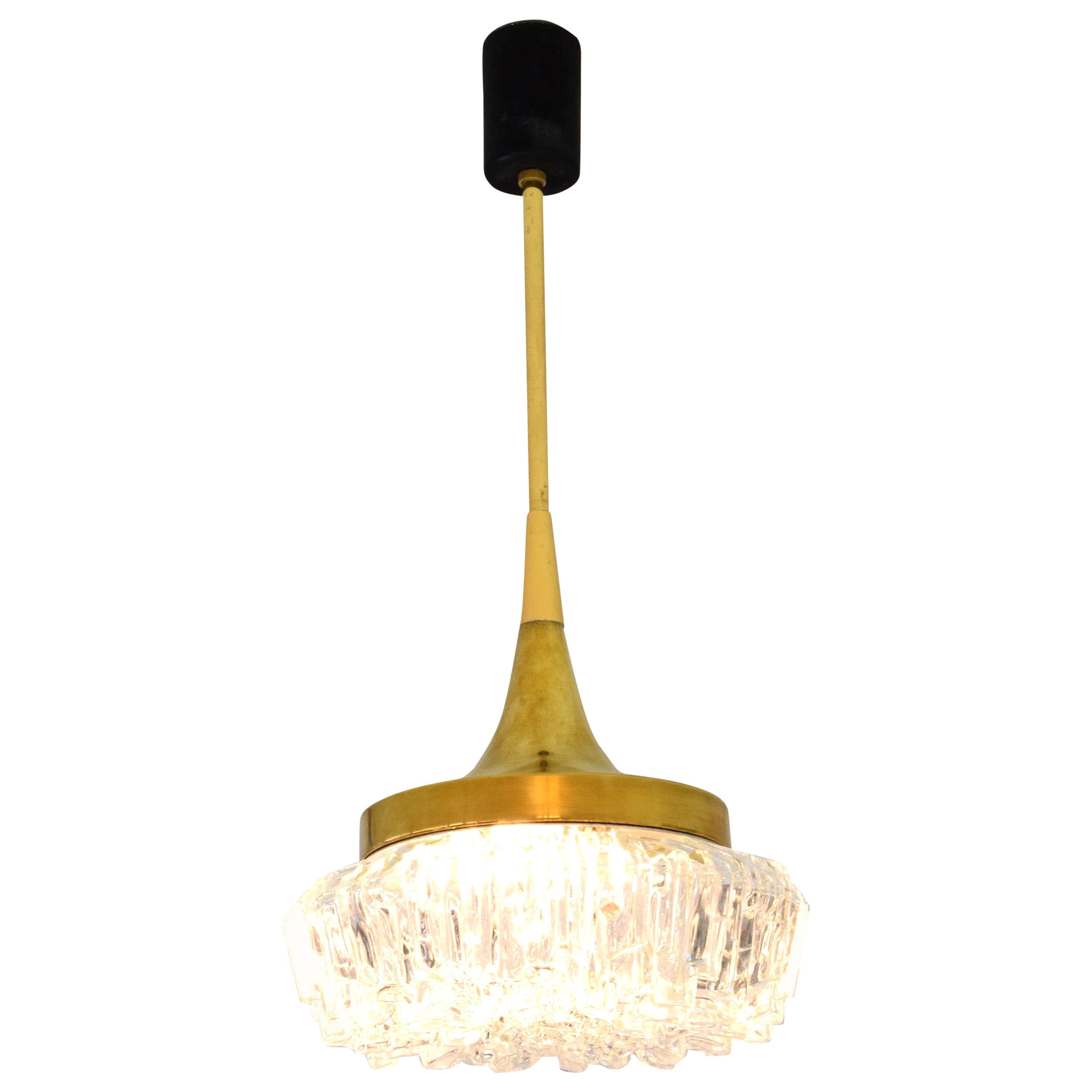 20th century French vintage pendant light composed of a slender polished gold brass structure and a single textured cut-clear glass shade in beautiful condition. 
Of Hollywood Regency style. Attributed to DLG Arlus. 
France, 1950s. 
The brass may