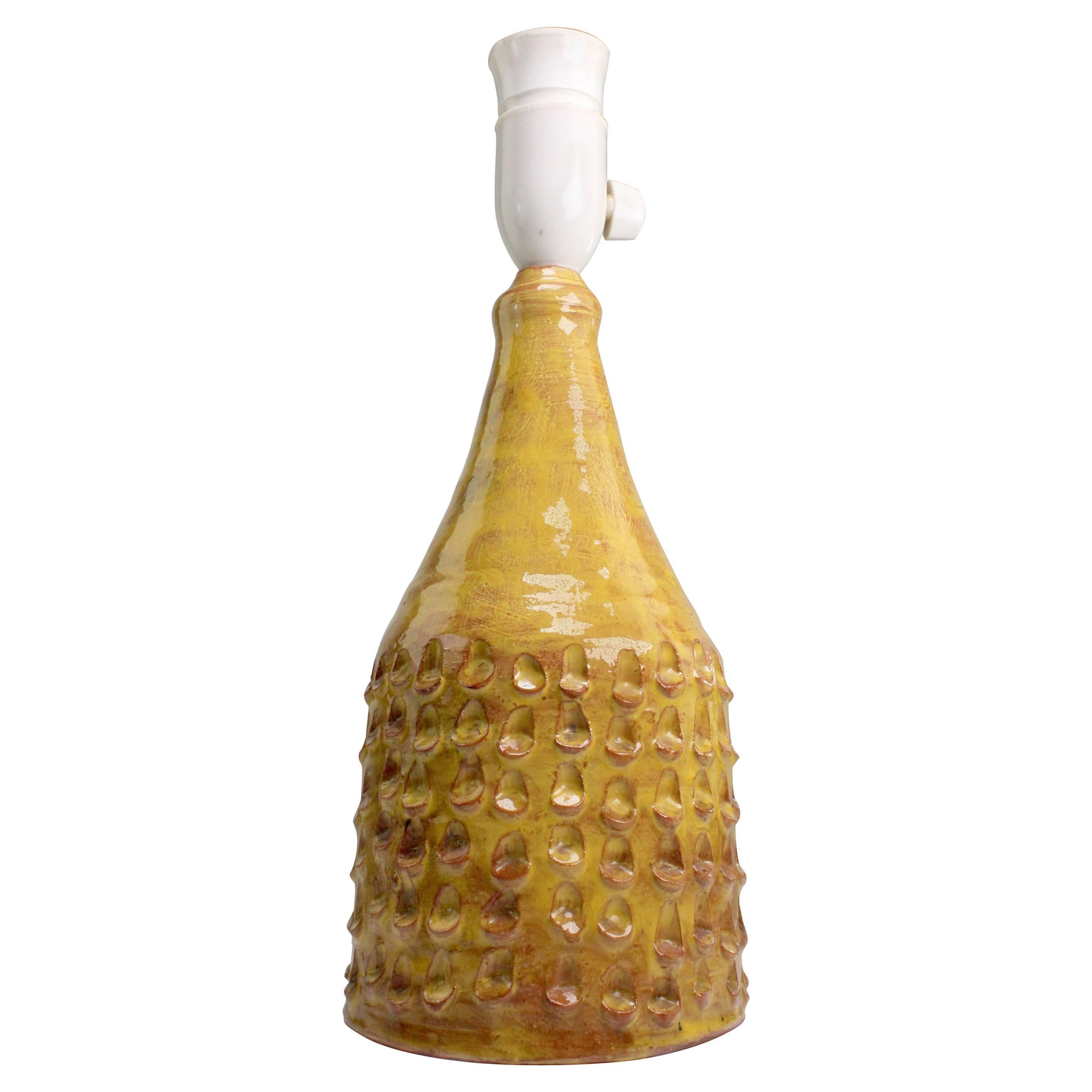 Lampe de table en céramique moderniste danoise faite et décorée à la main, avec de petites vagues organiques arrondies autour de la panse, conçue par Frølich au Danemark dans les années 1960. Glaçage de couleur curry doré qui laisse transparaître