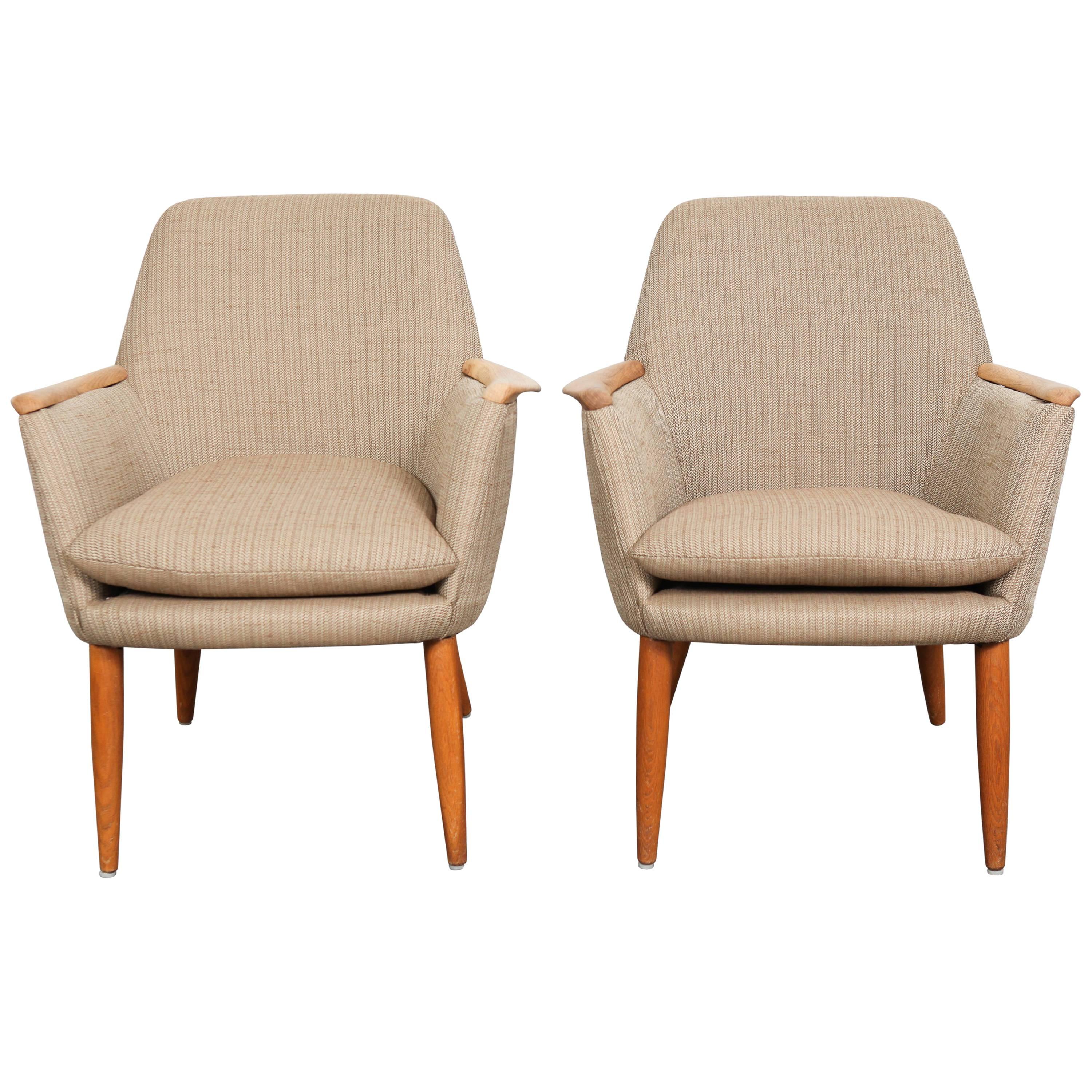 Pair of comfortable Mid-Century Modern Swedish lounge chairs with lipped oak arms and round teak tapered legs. These chairs have been recovered in new beige upholstery.