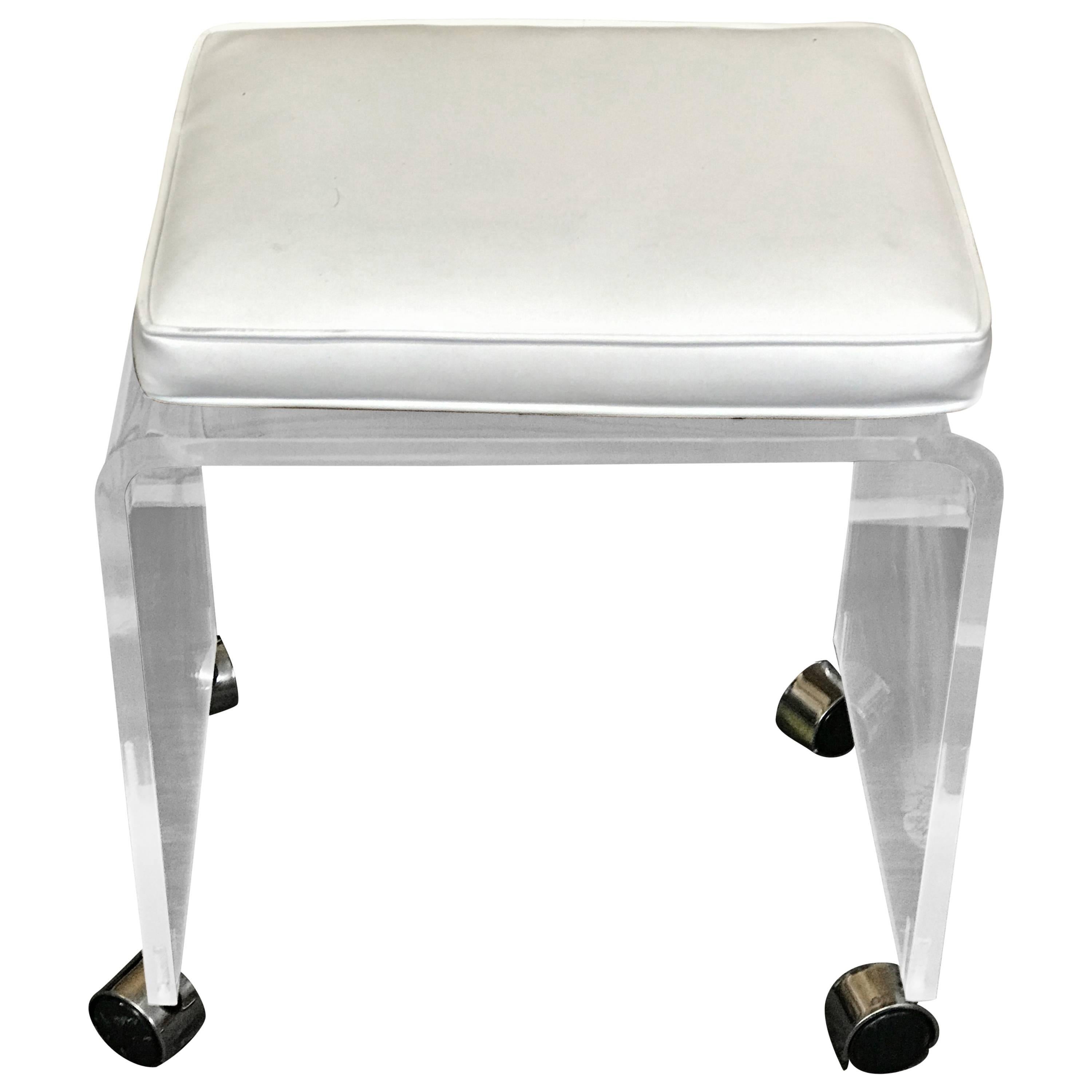 Lucite bench or stool with white Naugahyde cushion raised on chrome casters. The removable cushions measures 17" x 12"x 2" high. The bench as shown with the cushion has a seat height of 20" or 18" high without the cushion.