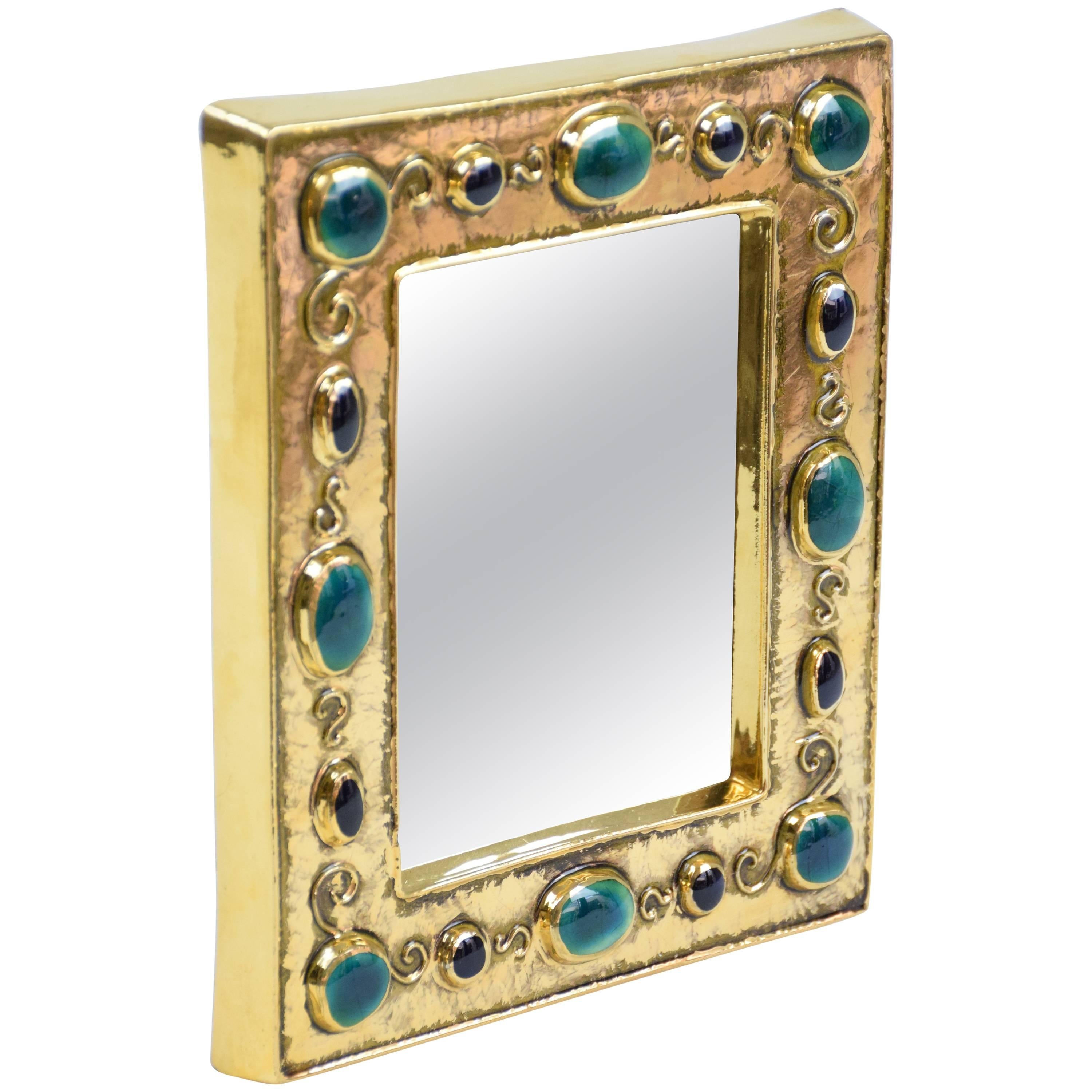 20th century vintage collectible 'Jewels Mirror' handcrafted by French artist François Lembo in the 1960s. This statement piece is crafted out of gilded and enamelled ceramic with black and green glass cabochons imitating natural