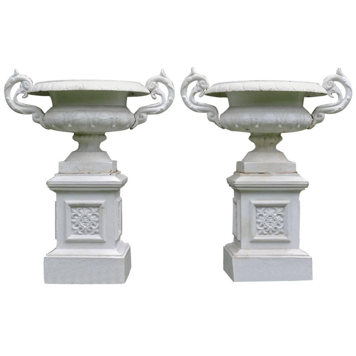 A Pair of White Painted Cast-Iron Urns on Pedestals