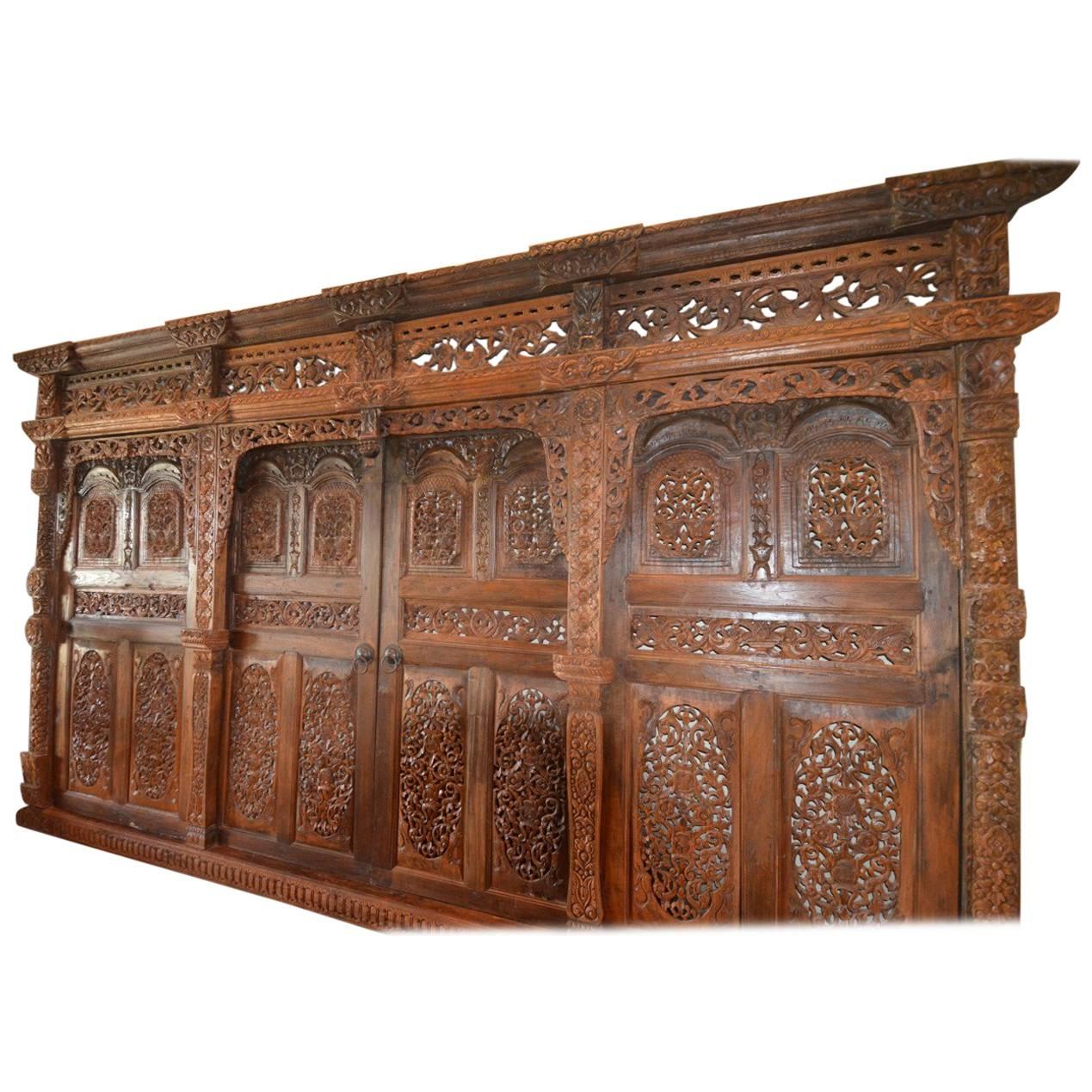 It is extremely rare to find a piece like this outside of Indonesia. Elaborately carved from teak wood this twelve foot architectural piece consists of a frame housing two side doors and a sliding double door in the middle.
This was purchased in