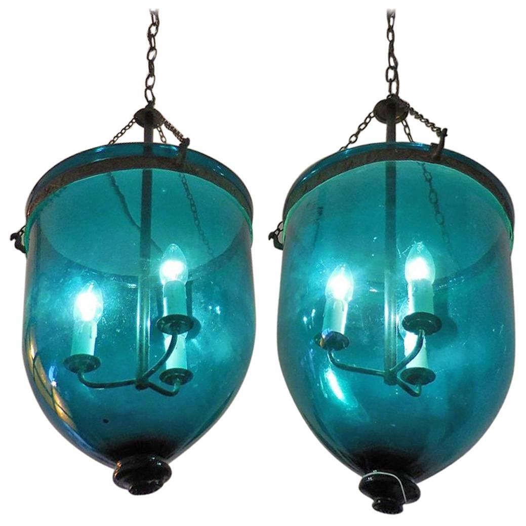 English bell jar hall lanterns, these where made at the end of the 19th century and later rewired to electric, they have a beautiful green/blue glow in the glass and hanging in a brass frame with peacocks heads where the chains are mounted on. Both