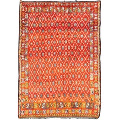 Tapis marocain vintage à fond orange et rouge avec motif de diamants sur toute sa surface