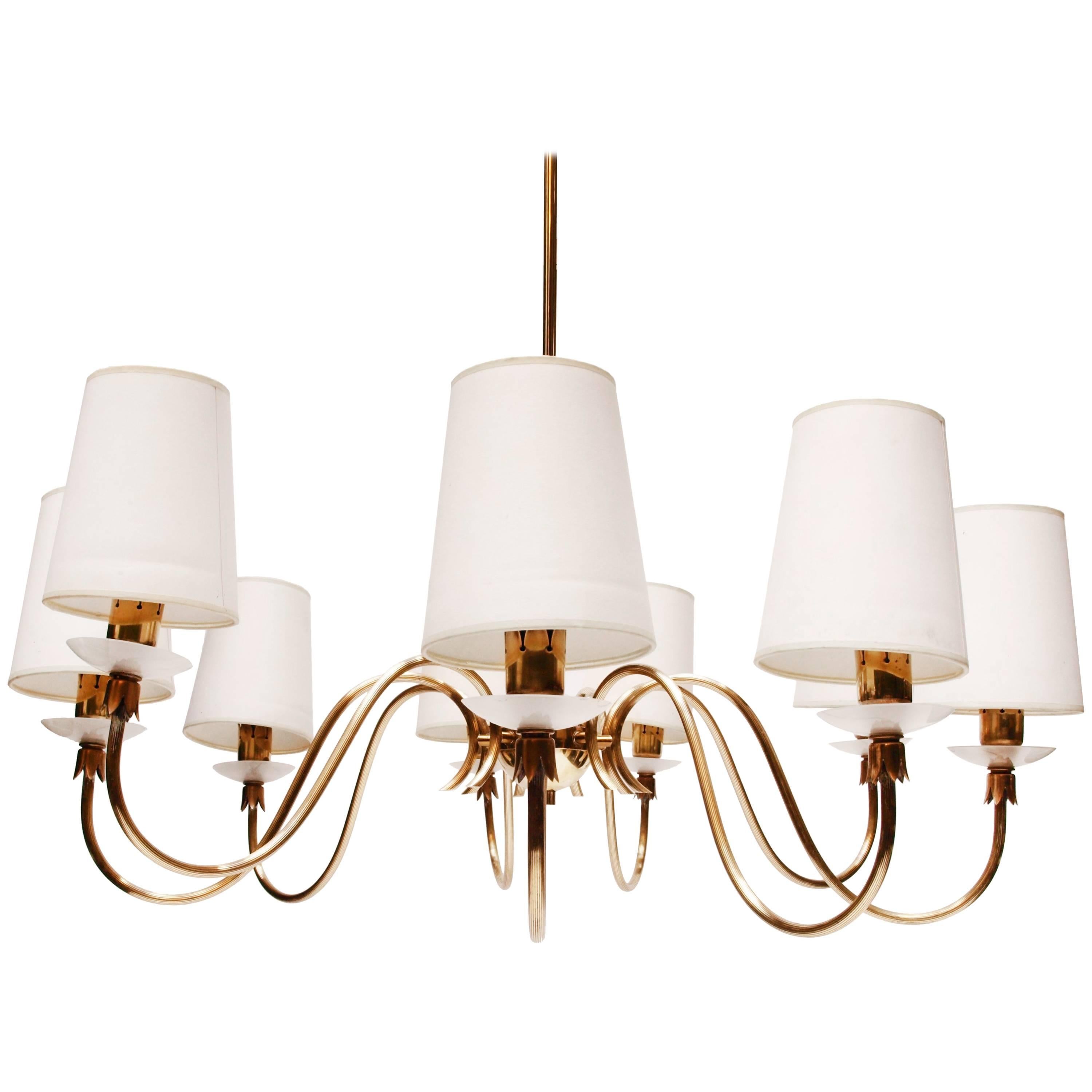Elegant scrolled 9 arm chandelier by Angelo Lelli for Arredoluce model no. 12834. Classical but transitional in design, with distinctive candle lightbulb holders. It is held from the ceiling by a brass rod of modern circular design. The arms feature