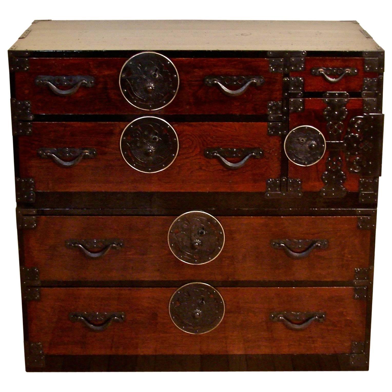 A fine Japanese Meiji period lacquered and stained choba or clothing tansu in two parts, the upper stage with two short drawers and a safe compartment containing two further small drawers, the lower section with two long drawers, the pine sides with