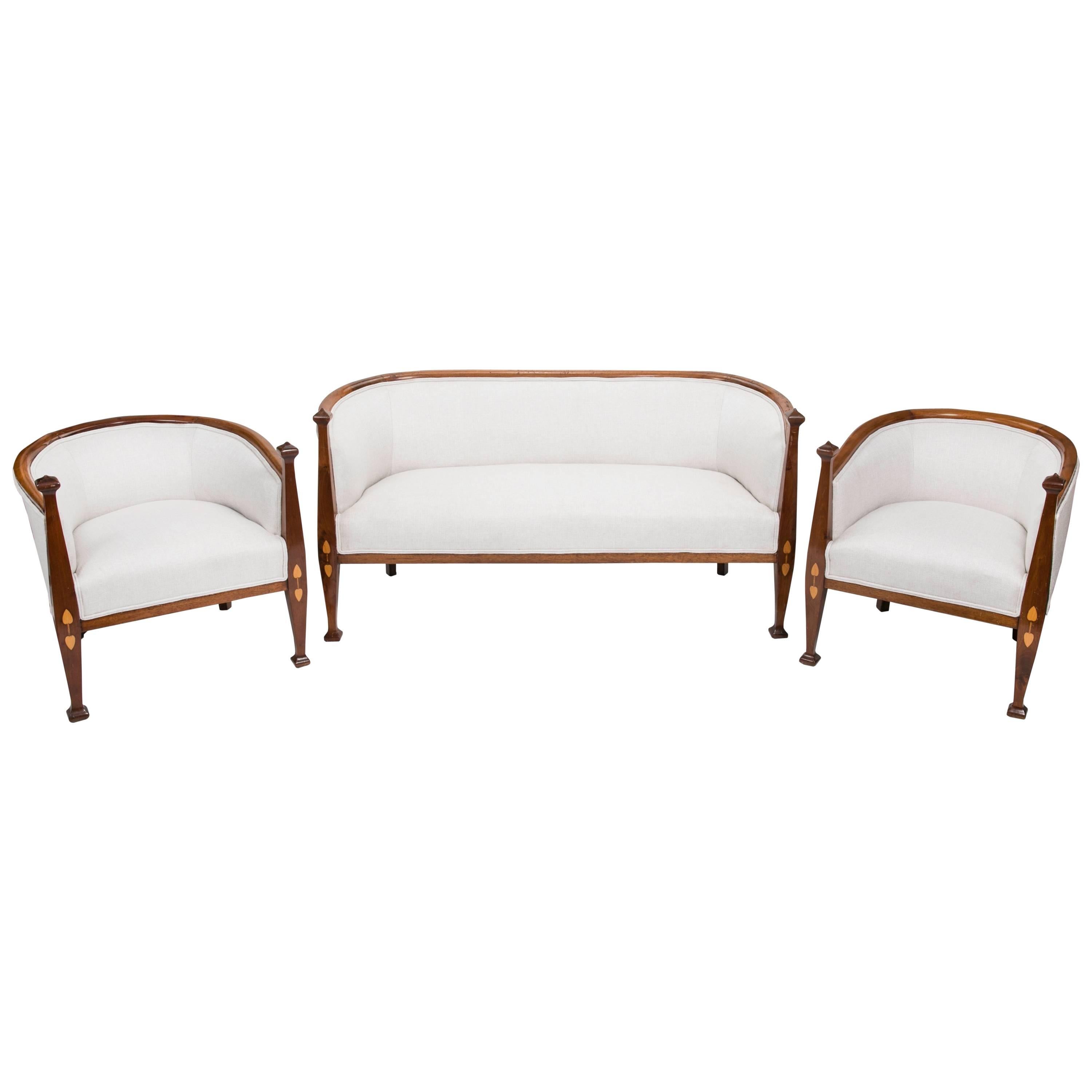 Art Nouveau period three piece set.  Settee and pair of arm chairs.   Beautifully carved walnut wood frame with arms in pod shape posts. The pod design is beautifully  Inlaid on the front  leg posts.  The inlay is done in contrasting light satin