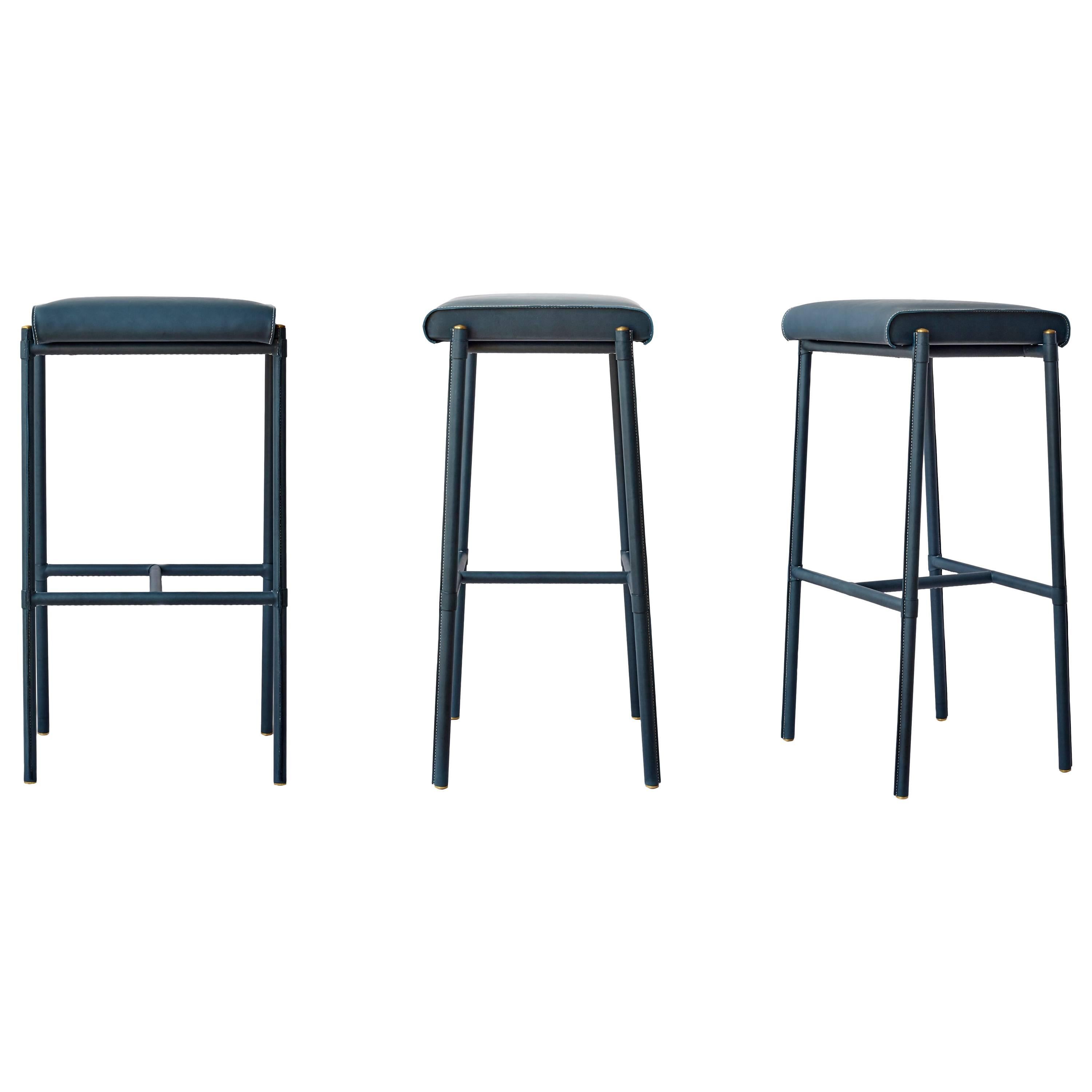 The JACQUELINE Stool was created as a tribute to Jacques Adnet's mid 20th-century leather stools with a modernized height, leather color, and hand-stitching. The stool is expertly executed in a dynamic teal with ivory hand- stitched detail and