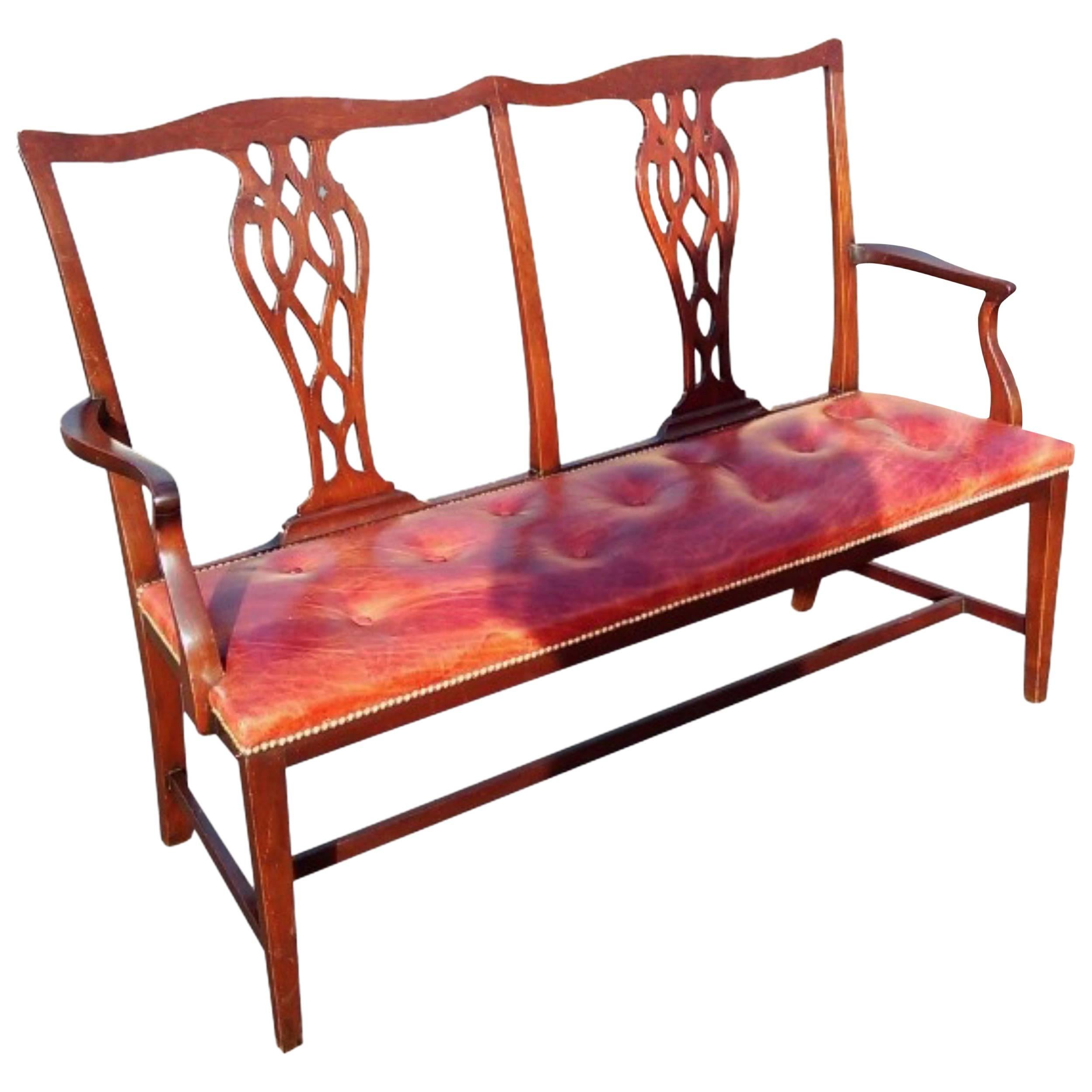 Elegant 19th century mahogany chair back settee; the twin chair backs with shaped crest rail and two vase shaped pierced splats on a buttoned red leather upholstered seat with a brass studded edge; the shaped arms with scroll supports; standing on