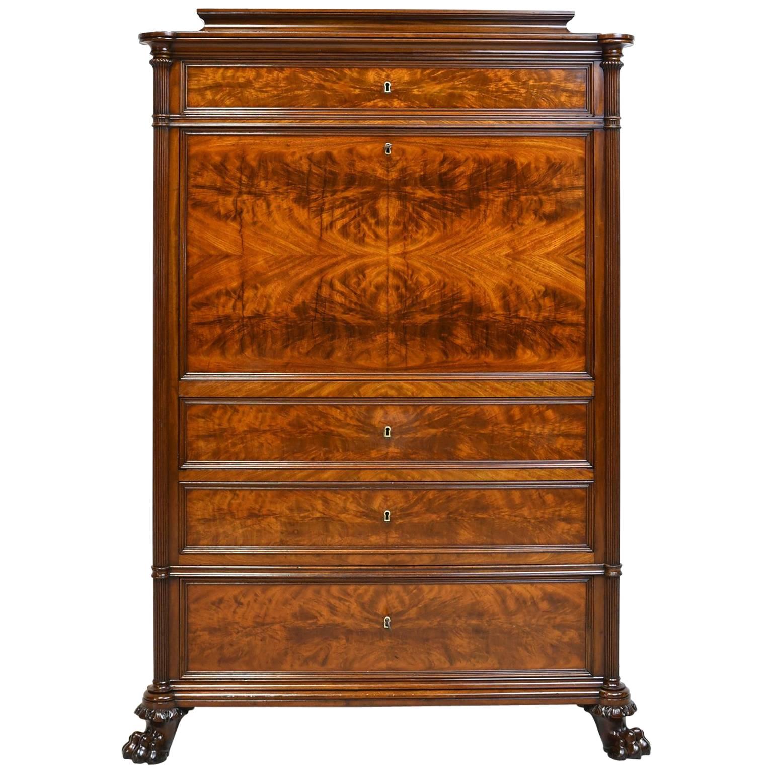 An extremely handsome secretary in fine West Indies mahogany with pedestal top above top drawer, and a birch inlaid drop-front opening to a desk with a long open storage area for papers below a series of fitted drawers that are in mahogany banded in