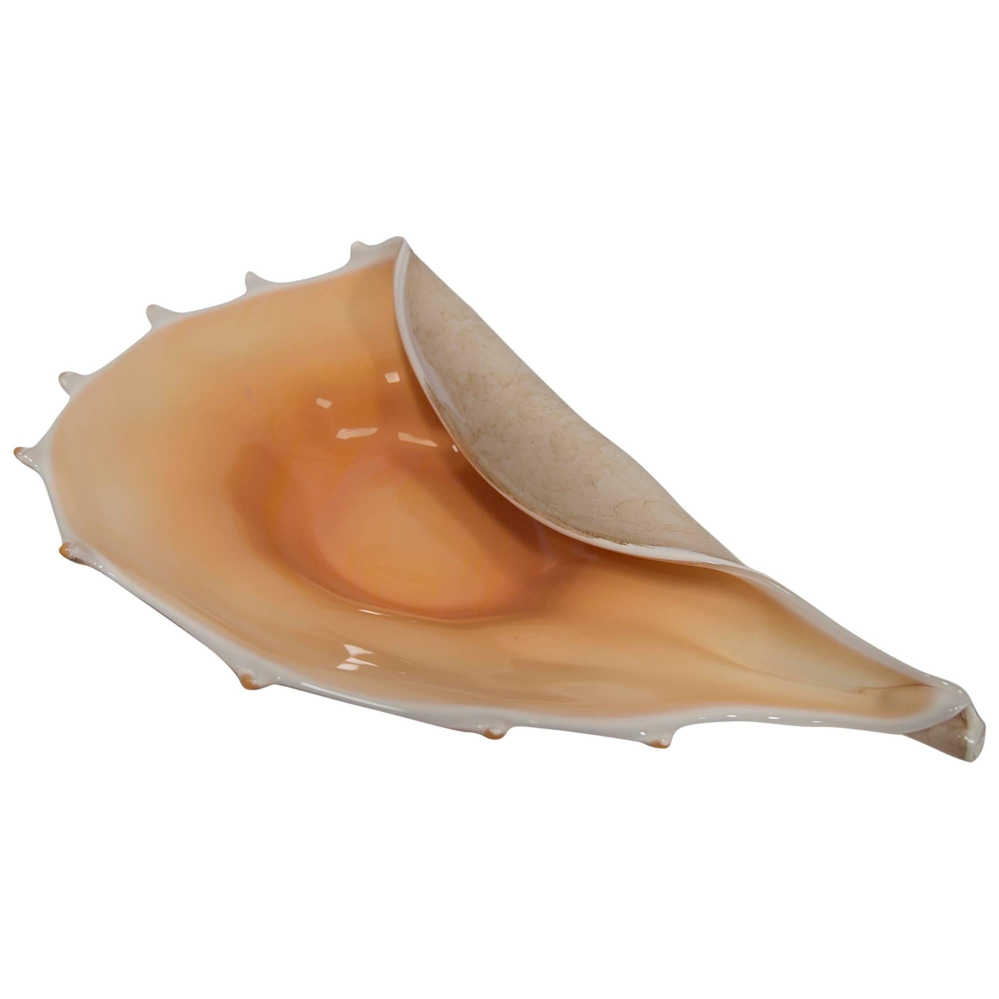 An impressive large-scaled Italian shell-form glass bowl. Artist unknown but this piece is quite realistically rendered in a conch shell form with smooth, luminous interior. The scalloped edge has pointed spines above an underside with brown