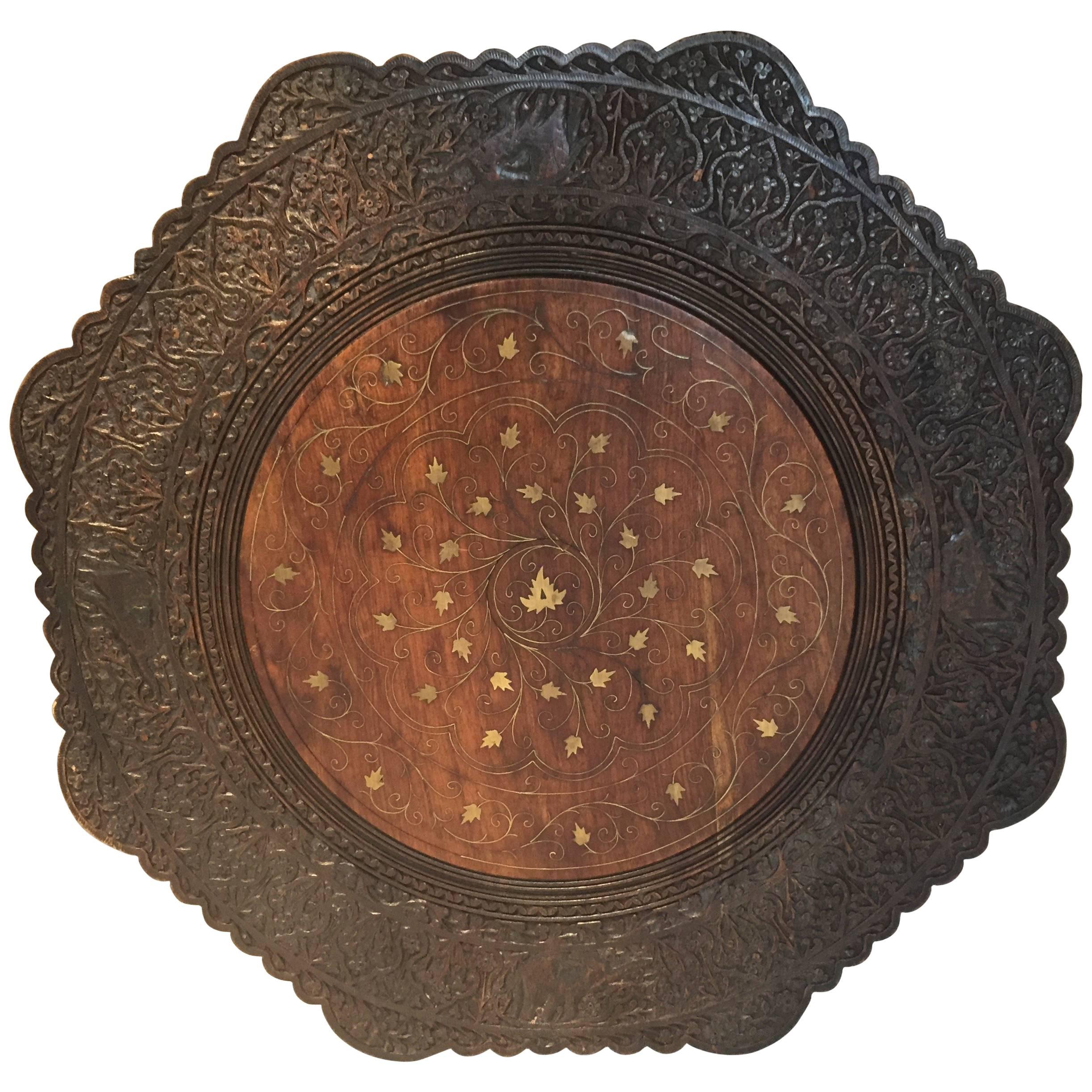 Fine quality exotic mahogany Anglo-Indian pierced hand-carved octagonal table, circa 1880. 
The top features an round panel with an inlaid brass floral design surrounded by elaborate leaf and flower carvings. 
Elaborately carved octagon paneled