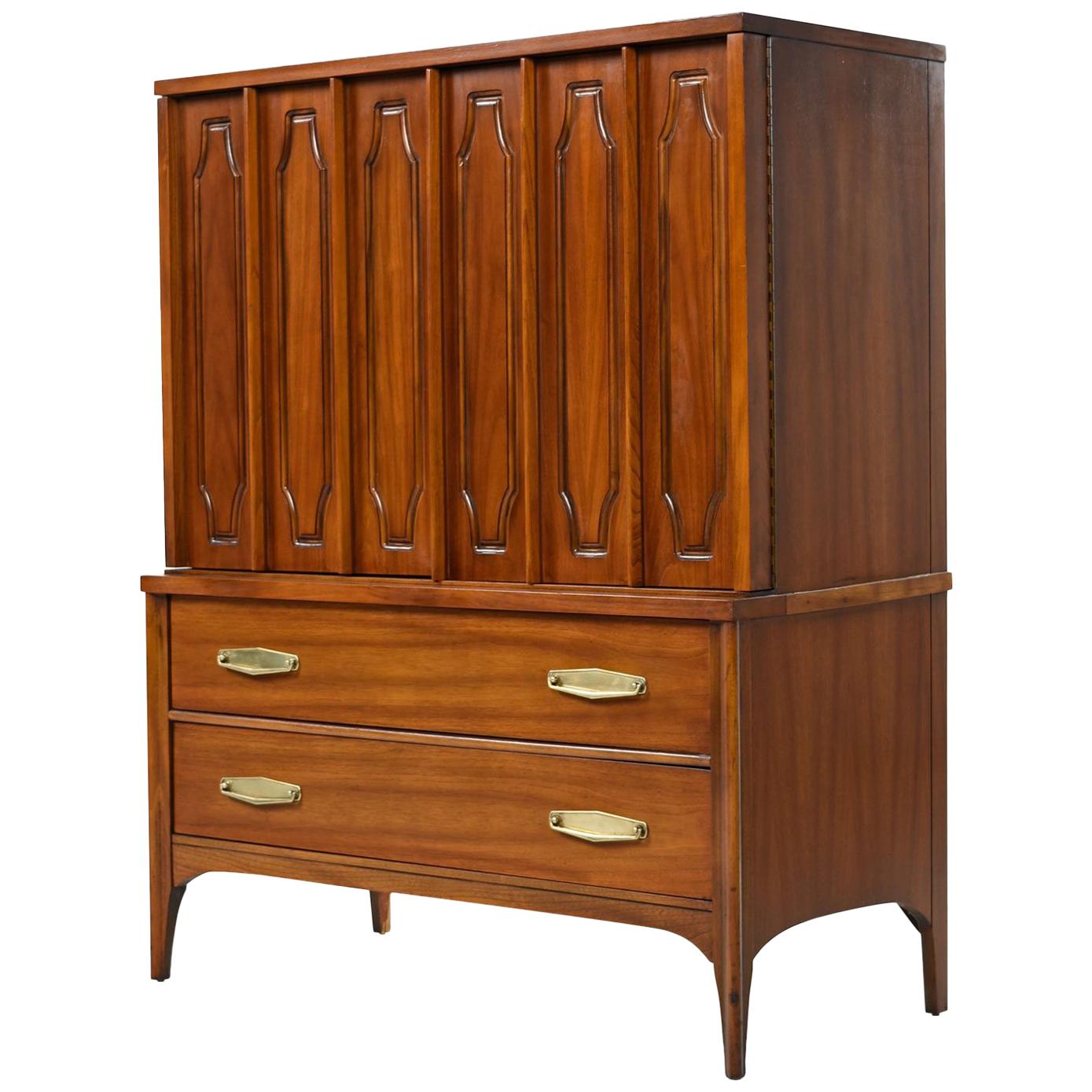 This gorgeous gentleman's dresser created by Kent Coffey for the Marquee Modern line boasts a beautiful finish that celebrates its walnut grain. The top portion features two cabinet doors that open up to three large drawers for storage. Below are