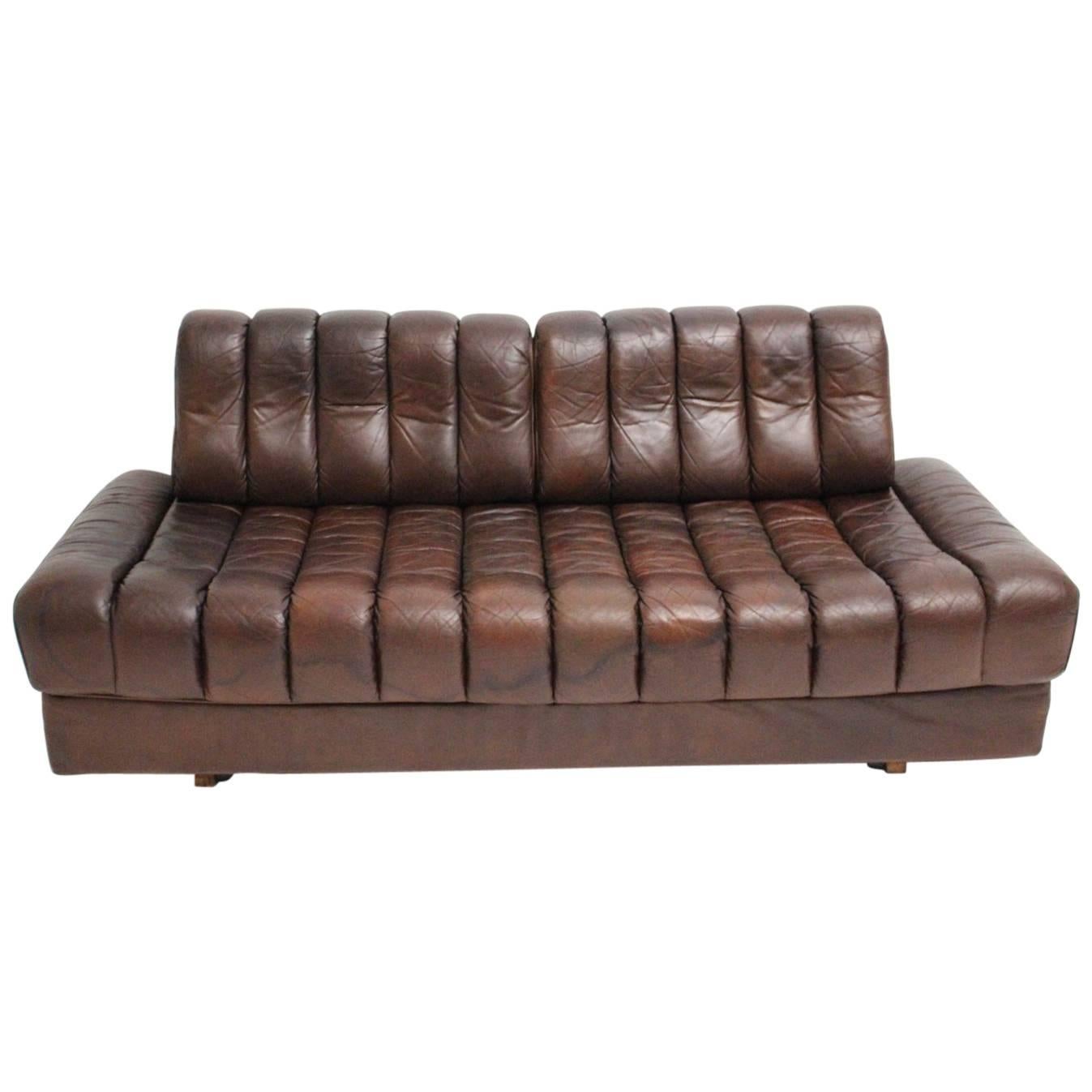 This vintage leather love seat has a special feature - to unfold by one hand into a daybed for two persons.
The leather surface has a great leather patina and the color is a wonderful warm chestnut brown.
This bench has a tube steel bracket on the