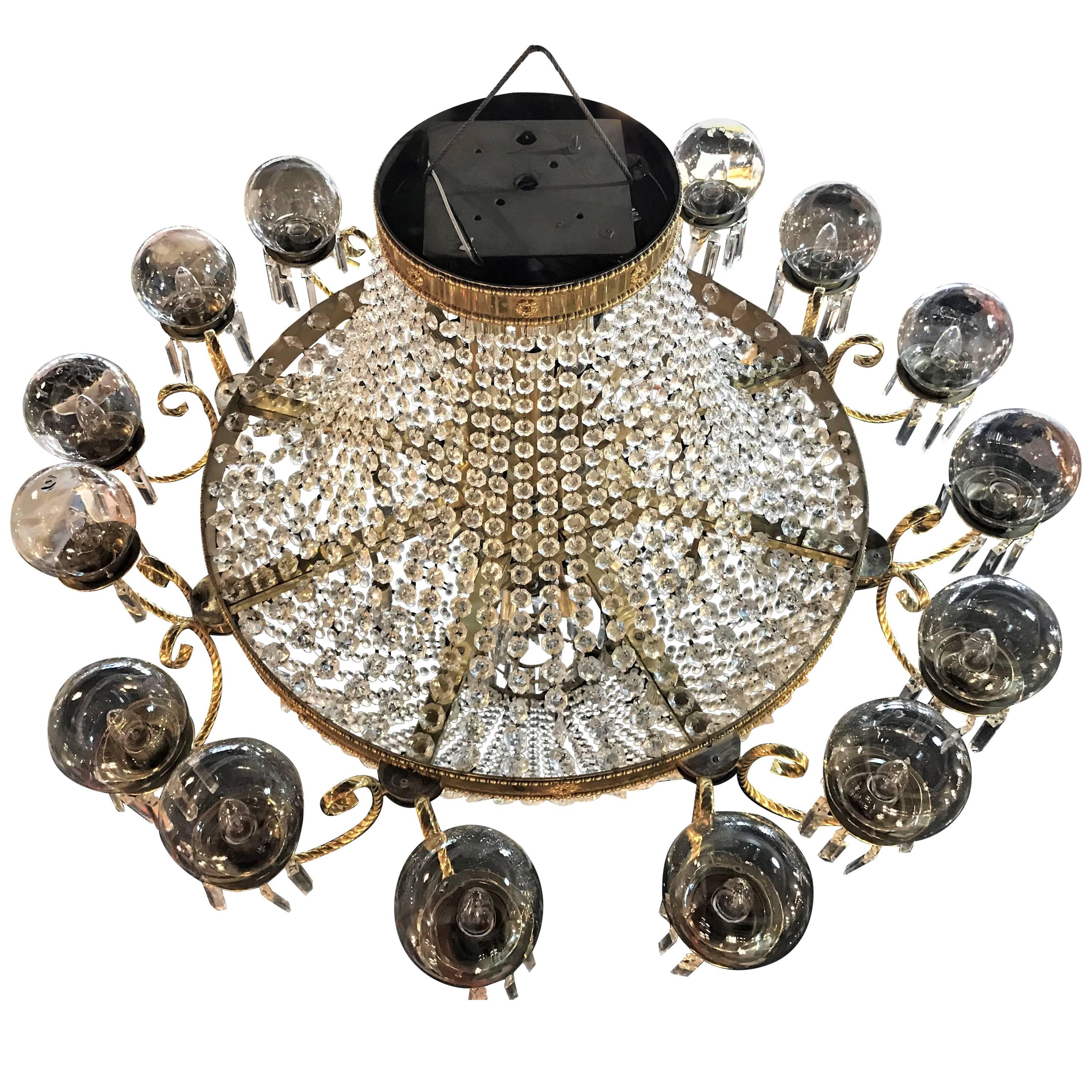 A palatial neoclassical style brass and crystal basket form chandelier with Hanging Prisms. Having 16 globe covered lights on brass circular plates and an interior holding too many lights to count, this astonishing chandelier is magnificent in not