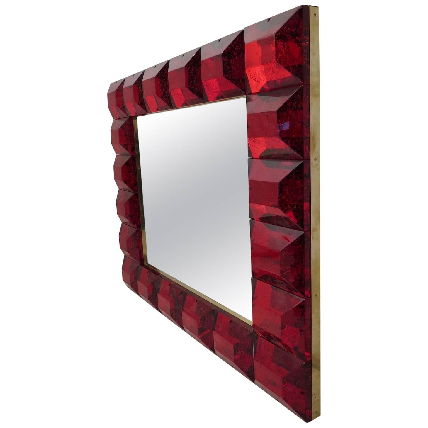 A strong purple red frame, reach the eye of the beholder, leaving him entranced; of Murano red art glass wall mirror. 

The structure of the wall mirror is in wood, where the red Murano glass is housed. The frame of the mirror is made up of a series