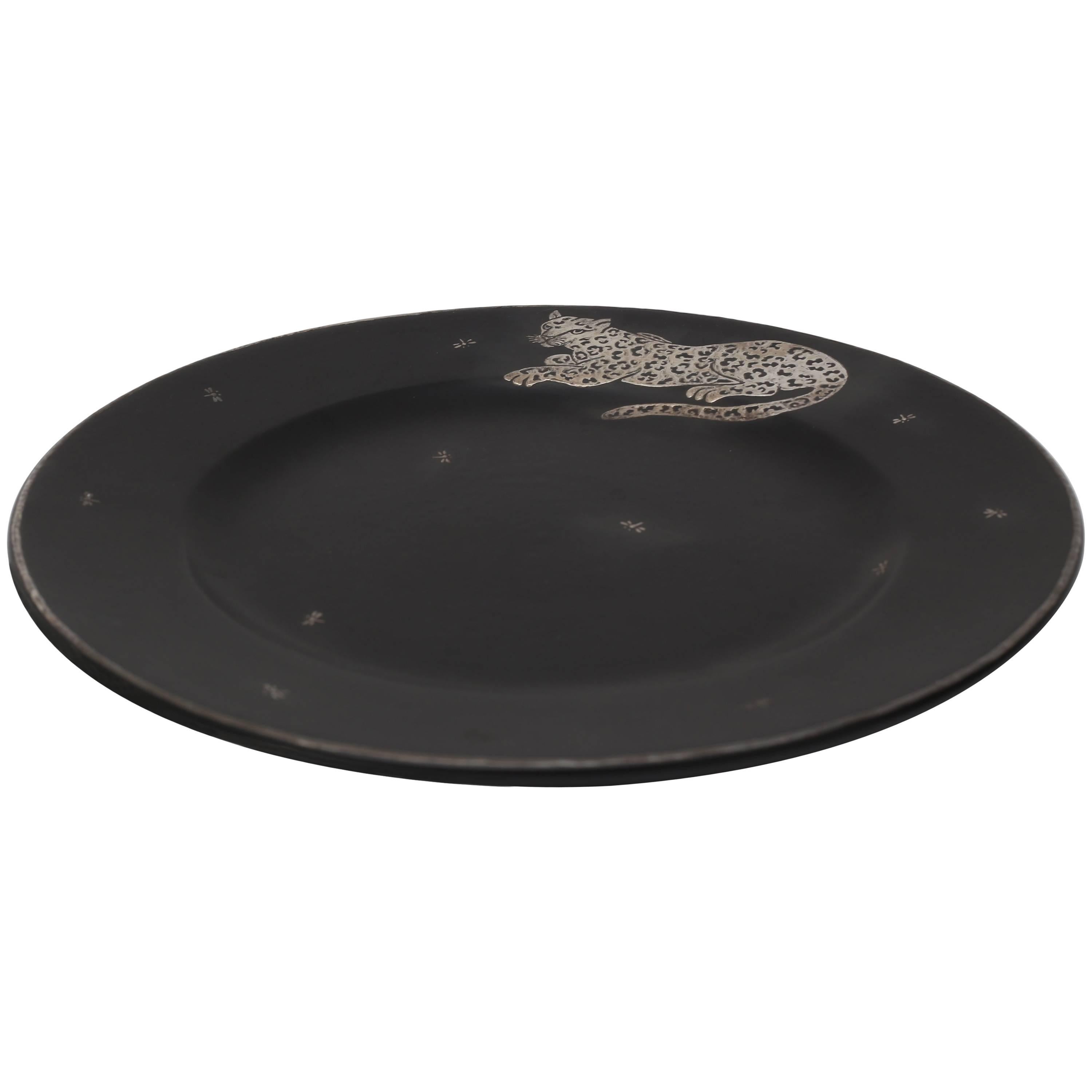 This stylish charger plate was created by Emilia Castillo and date to 2009. The basalt black coloration and sterling silver overlay of the jaguar and dragonflies makes for a charming and striking piece.

Note: Signed and dated on the reverse (see