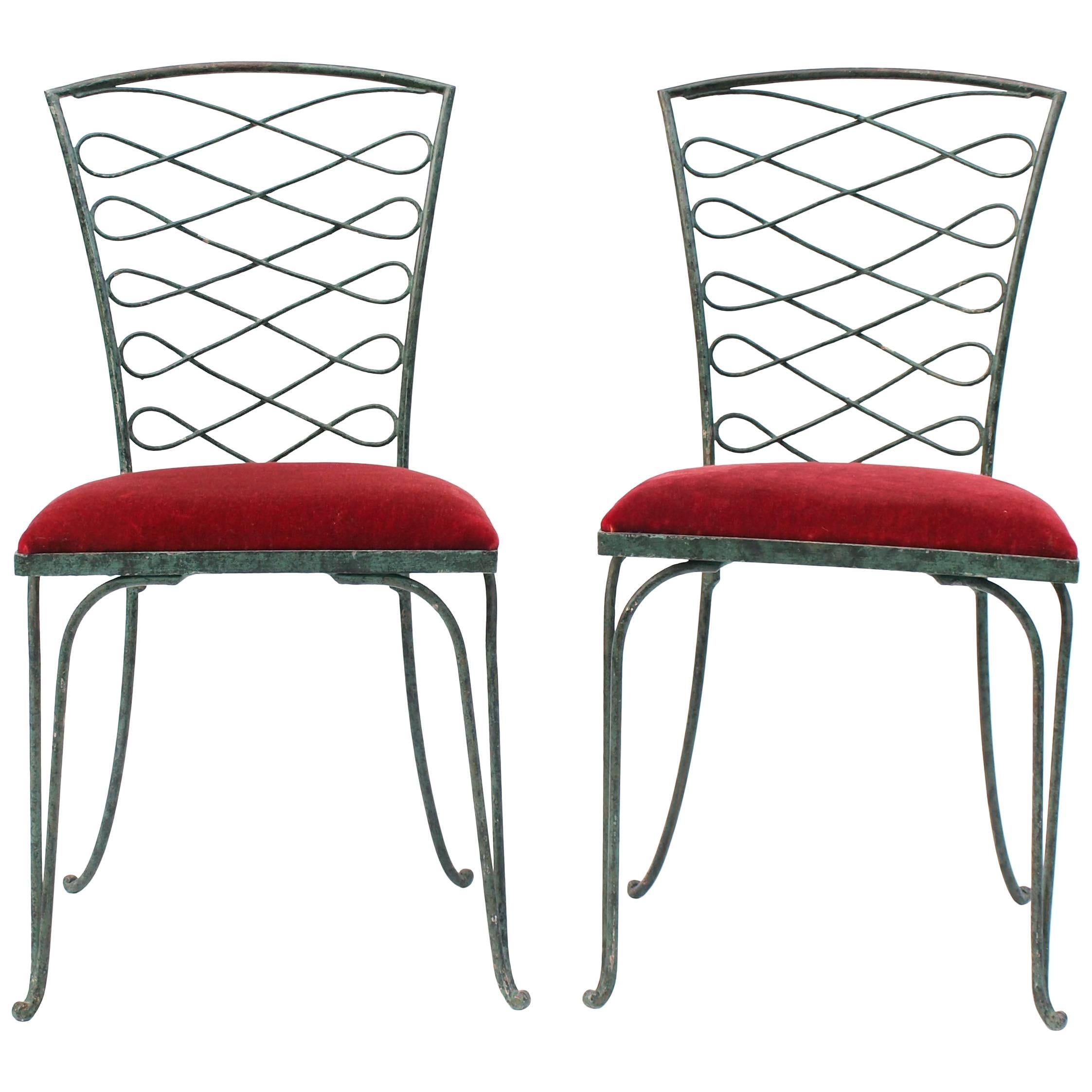 A pair of Rene Prou wrought iron chairs with a Verdigris patina. The backs have a decorative iron work scroll pattern of repeated form that rest on a subtlety turned ball foot and upholstered in red velvet.