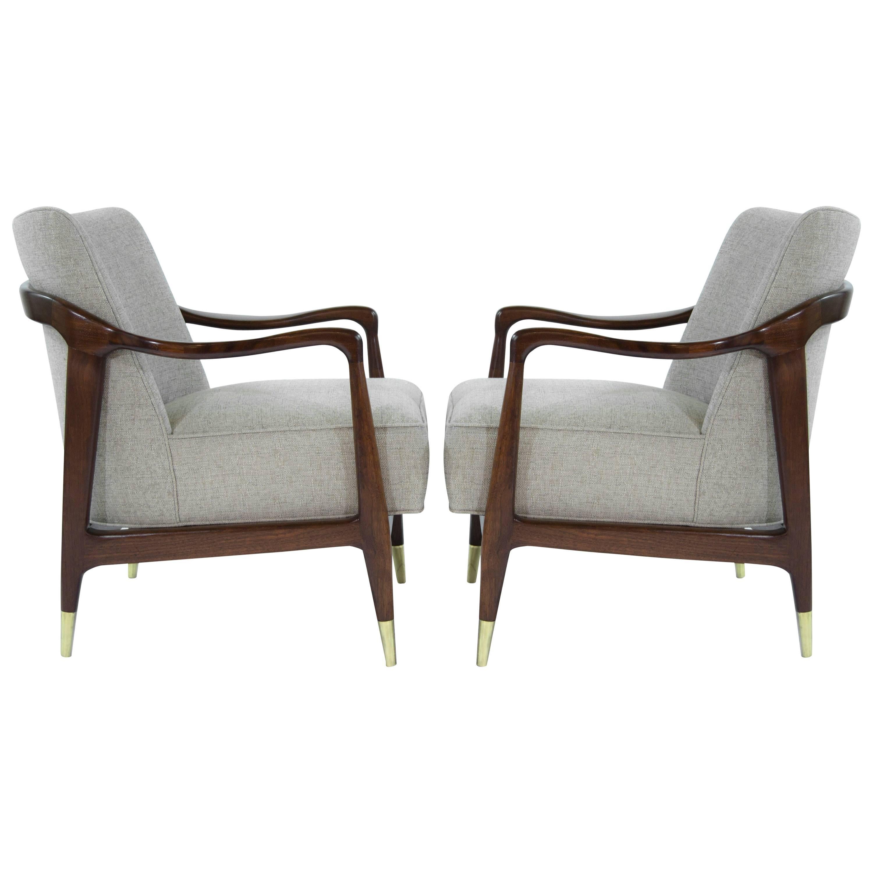 Rare pair of Italian lounge chairs featuring sculpted walnut frames and brass sabots. Walnut frames fully restored, newly upholstered in sand linen.