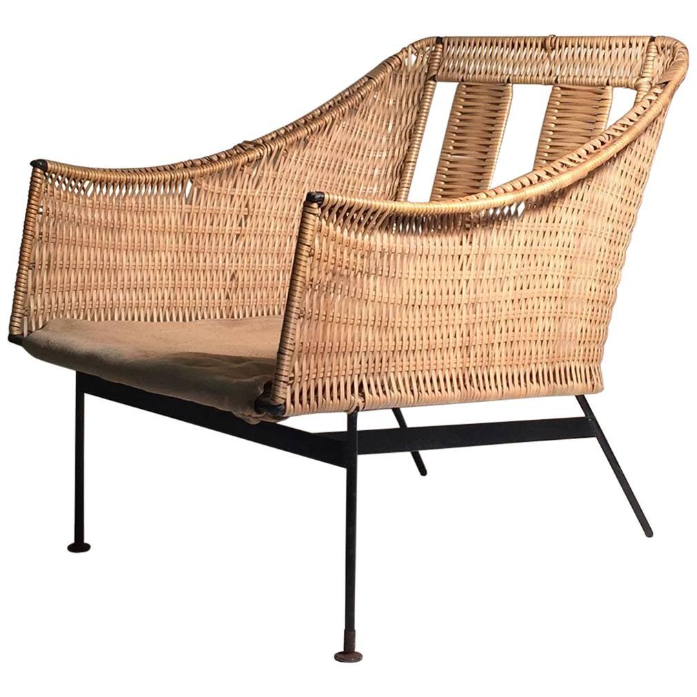 Uncommon early form by Tempestini for Salterini. Wrought iron with a faux wicker or rattan in a plastic of sort. A nice example of Tempestini's period design. Just needs cushions. Some mild wear to frame. A couple areas on the plastic wrap that