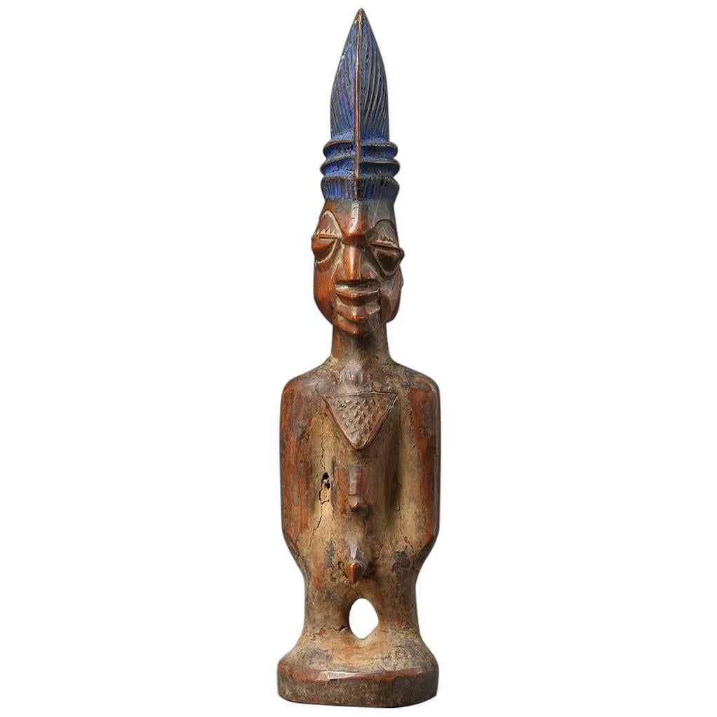 A finely carved male twin figure, ere Ibeji, Yoruba People, Nigeria, created in the early 20th century.
With a tall plaited coiffure, expressive eyes, and extensive wear and polish from native use. Areas of encrusted camwood powder between arms and