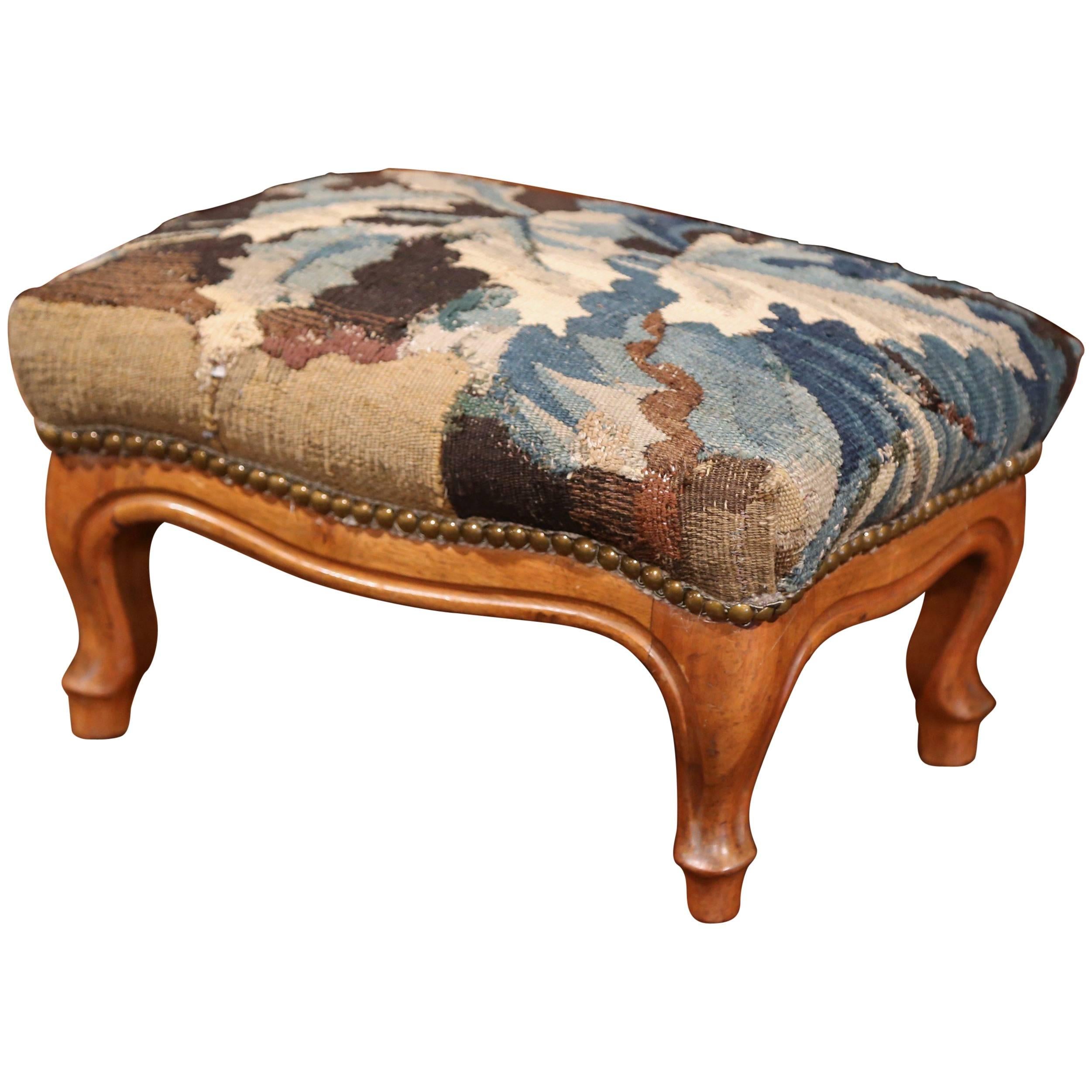 This elegant, antique footstool was crafted in Lyon, France, circa 1860. The carved, rectangular footrest has been reupholstered with old Aubusson verdure fragment in soft blue, beige, green and brown palette. The Louis XV stool is in excellent