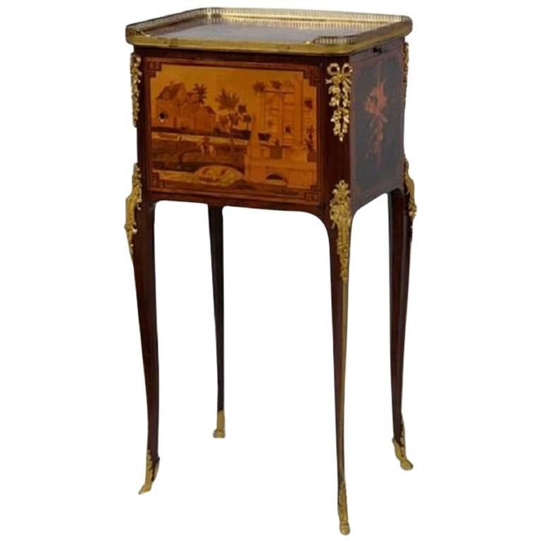 Cette exquise table d'appoint en marqueterie a été fabriquée en France au XIXe siècle, dans le style Transitionnel, incorporant à la fois des éléments néoclassiques et rococo. La table repose sur quatre pieds sabots en bronze doré, qui se prolongent