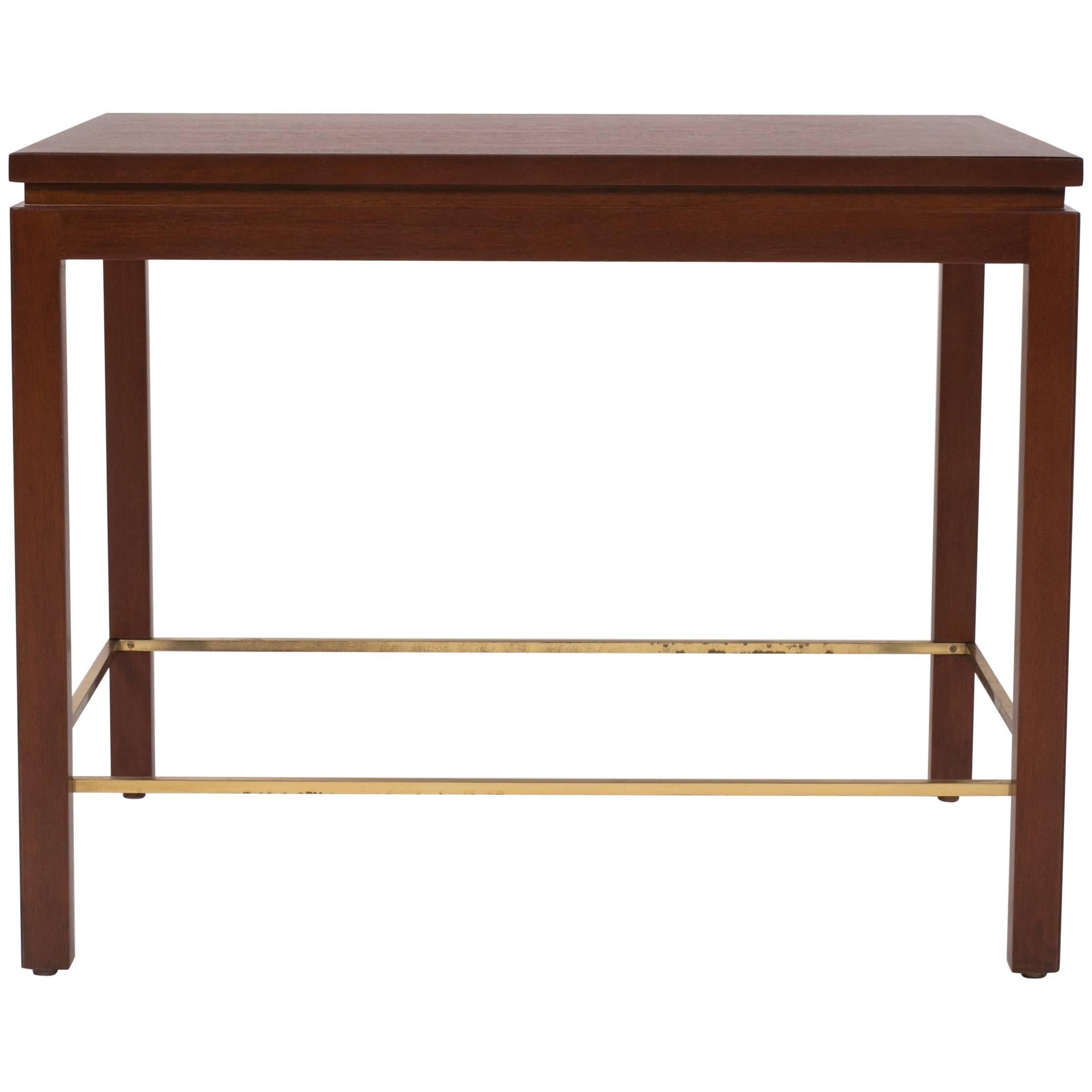 A nearly square side table designed by Edward Wormley for Dunbar. The model 310 has four square post legs that sit flush with the corners of the piece. Each leg is notched to fit a brass stretcher that defines the interior edges of the table. The