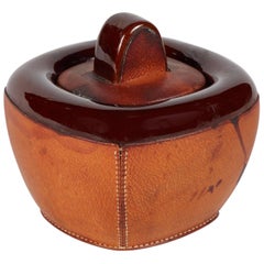 A Small Pottery Jar with Brown Leather Decoration and Lid
