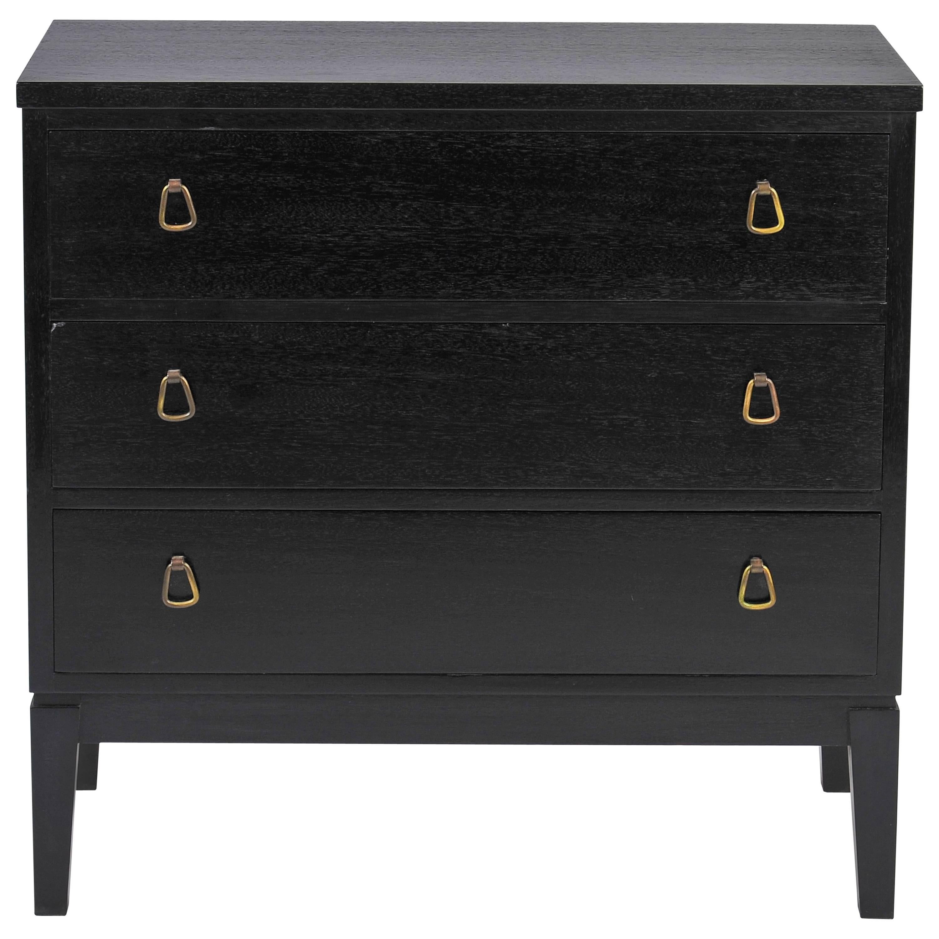 An ebonised teak chest of drawers, with brass handles
Denmark, circa 1970.