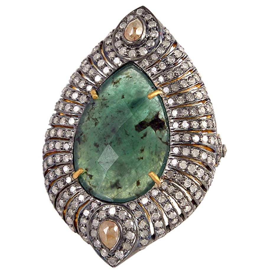 Anillo de cóctel de diseño con piedra esmeralda central rodeada de diamantes pavé