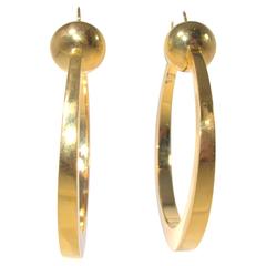 Large stylized gold hoop earrings, c. 1950.