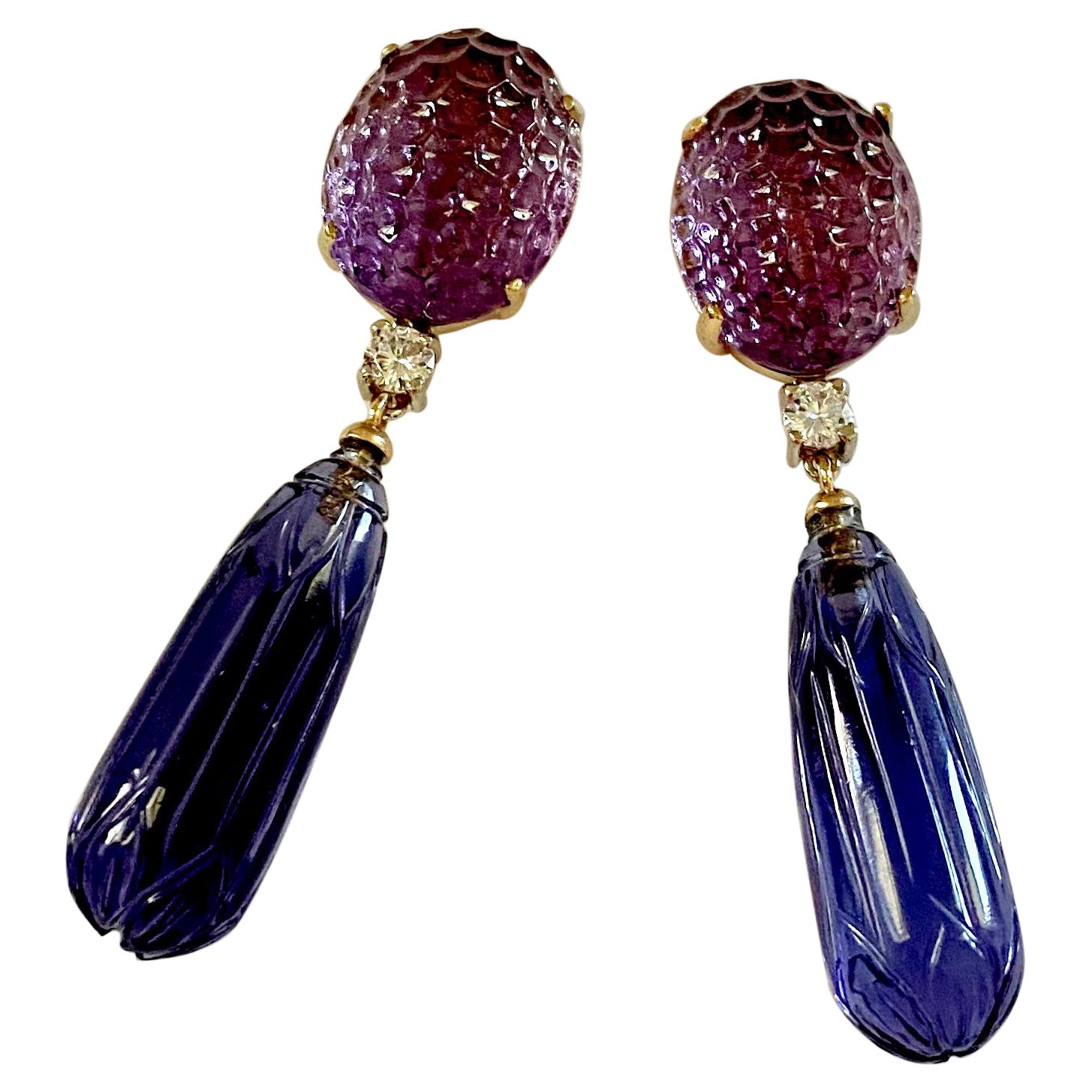 Purple amethyst (origin: Brazil) is paired with blue kyanite (origin: Tanzania) in these elegant dangle earrings.  The medium purple colored amethyst are carved in a honeycomb pattern.  The elongated kyanite drops are carved in a floral design. 