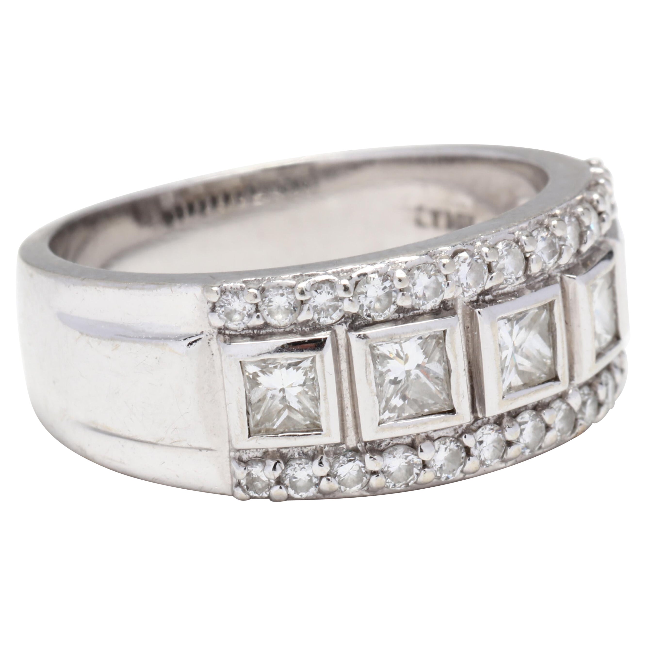 A 14 karat white gold princess and round cut diamond band ring. This ring features five bezel set, princess cut diamonds weighing approximately .90 total carats with a row of full cut round diamonds on either side weighing approximately .40 total