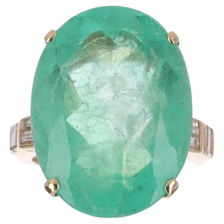 Behold! This stunning, emerald and diamond cocktail ring. The center stone carries a full 20.74-carats, of pure Colombian emerald beauty. Cut into the shape of an oval, and brought directly from the Muzo mines of Colombia. On either side, the large