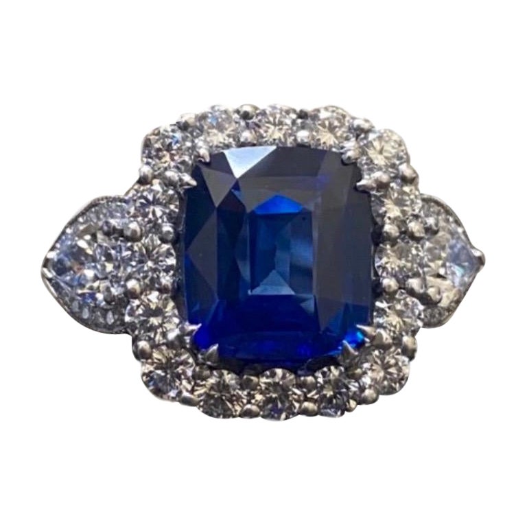 DeKara Design Kollektion Meisterwerk

Schöner Modern/Art Deco Ceylon Blauer Saphir und Diamant Ring

Metall - 90% Platin, 10% Iridium.

Steine- Echter Ceylon/Sri Lanka Royal Blue Sapphire im Kissenschliff 4,40 Karat. Zwei birnenförmige Diamanten, 4