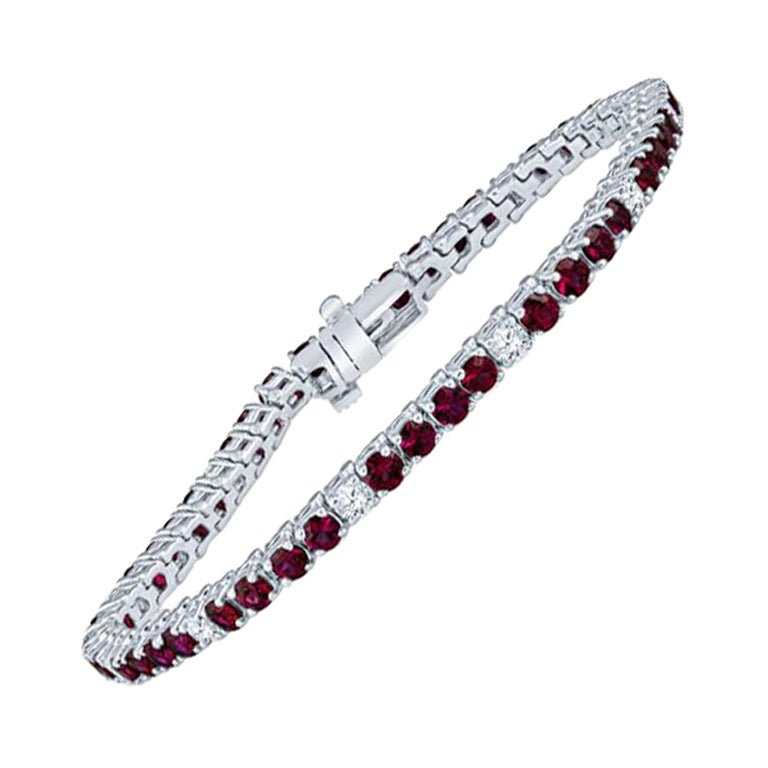 This tennis bracelet features 5.93 carat total weight in round rubies accented by 1.08 carat total weight in round diamonds set in 14 karat white gold. Box clasp with safety closure. This bracelet is 7