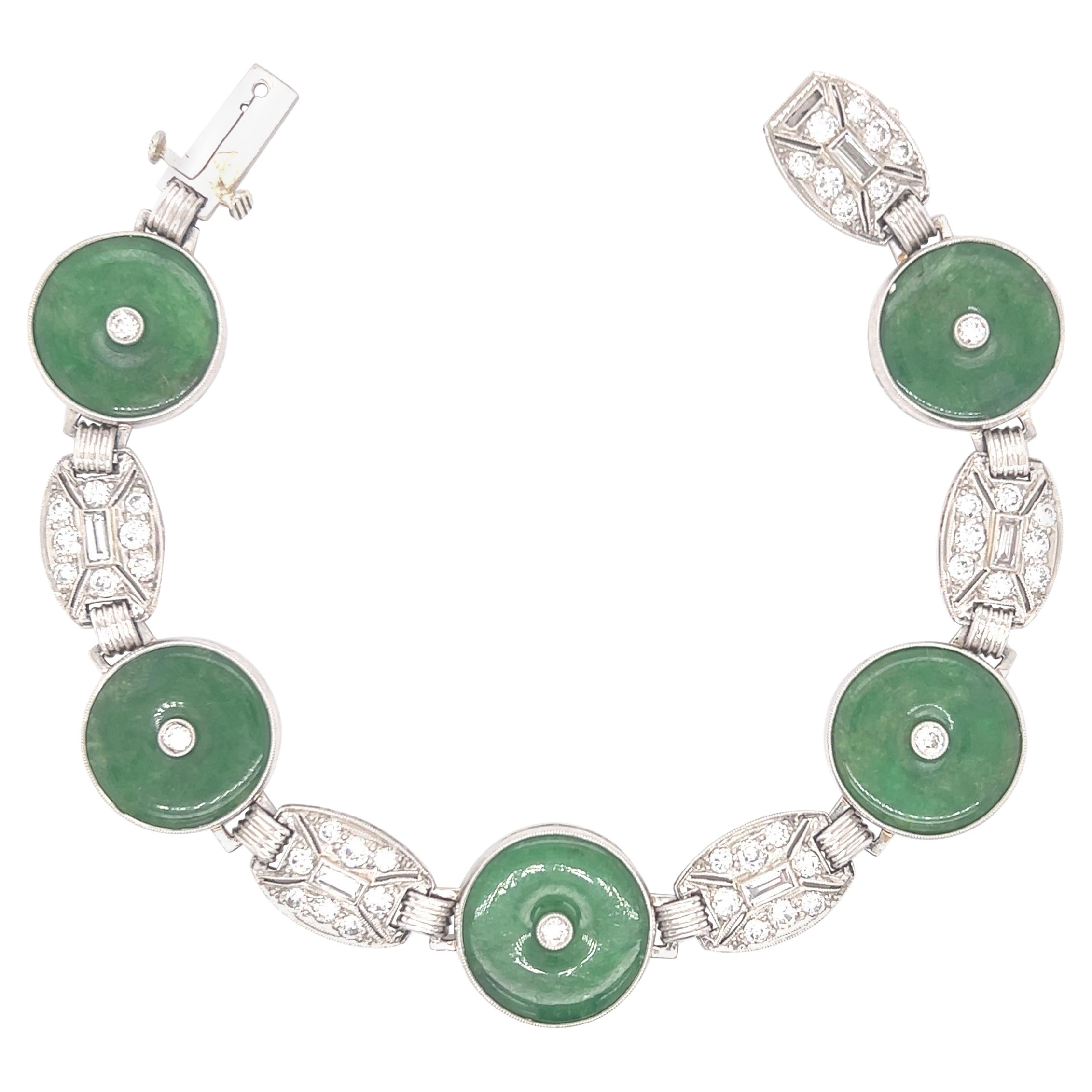 Beautiful Art Deco bracelet crafted in platinum. The bracelet is highlighted with five hololith shaped jade gemstones. The gemstones contain no impregnation and are 100% natural and earth mined. The jade gemstones display a vibrant green color that