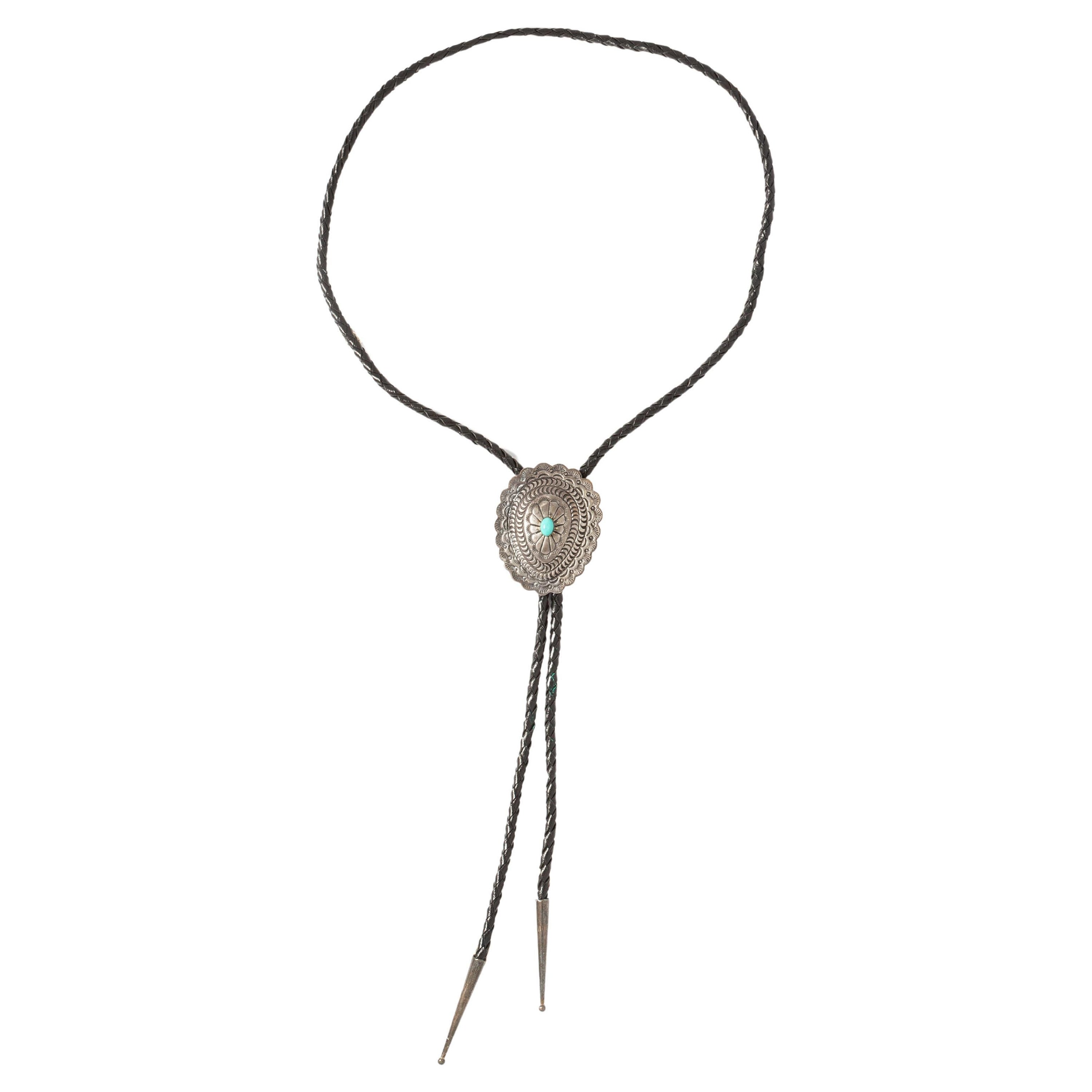 Bolo Tie silver-tone concho and tips.
One Turquoise (not tested) centering the concho.

Weight. 34.44 grams.
Length Pendentif: 5cm.
Width Pendentif: 4.20 cm.
Length Chaine: 96 cm.
