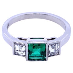 Anillo de compromiso de platino con esmeralda colombina y diamantes de 0.58 quilates y tres piedras