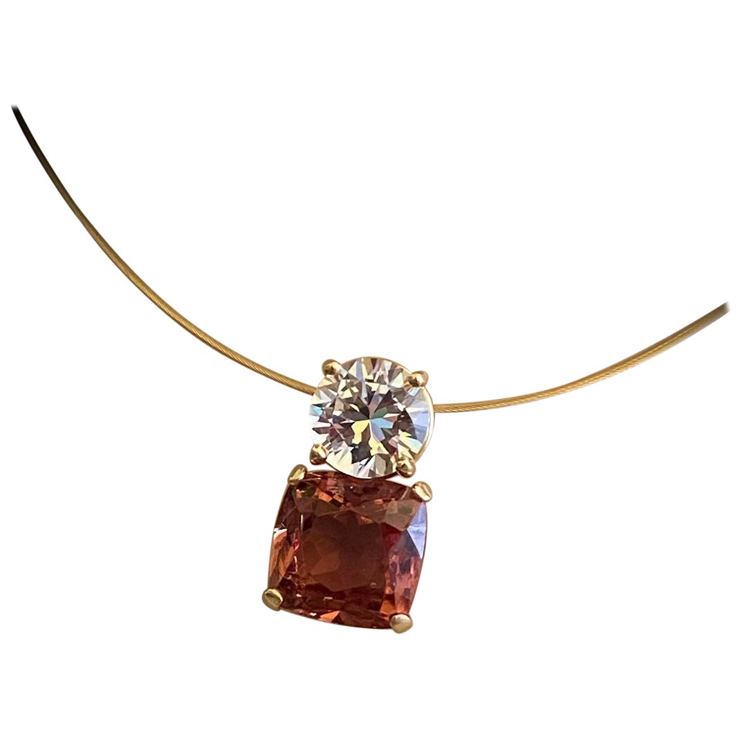 Zultanite and white sapphire are paired in this double gemstone pendant.  Zultanite (origin: the Ilbir Mountains of southwest Turkey) is a color change member of the diaspore family of minerals.  The gem shows peachy/pink color in natural or