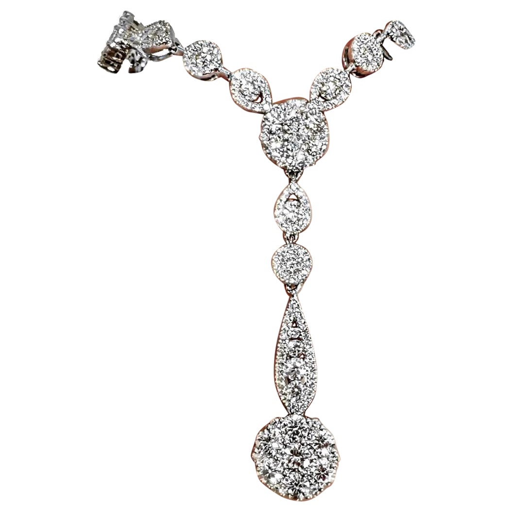 This modern design 18K white gold and diamond necklace absolutely shimmers and scintillates. The necklace measures 18 inches in length, and from the center hangs a 1 5/8 inch diamond encrusted drop. Crafted in a heavy and durable 18K white gold