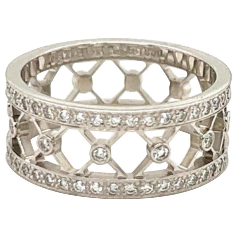 This gorgeous wide band ring is authentic from the Voile Collection by Tiffany & Co. It is 8mm wide with an open center with X design around the entire band. On each end of the band has a full circle of round cut diamonds and the center of each X