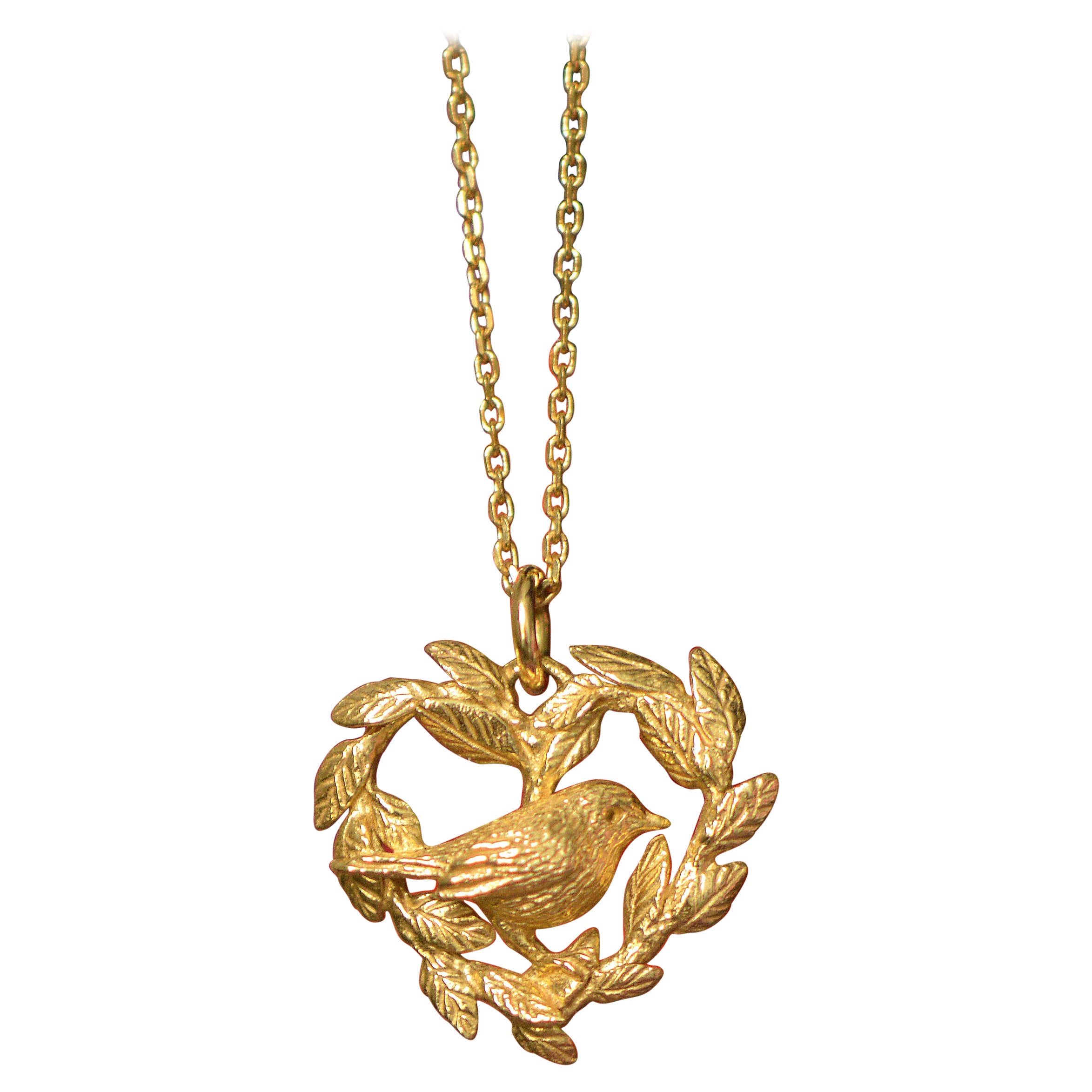 This robin perched on a heart shaped wreath pendant is cast in solid 18 Carat gold and finished by hand, and is created from Lucy's original hand-sculpted design. 

This robin pendant is made in London, United Kingdom using recycled or Fairtrade
