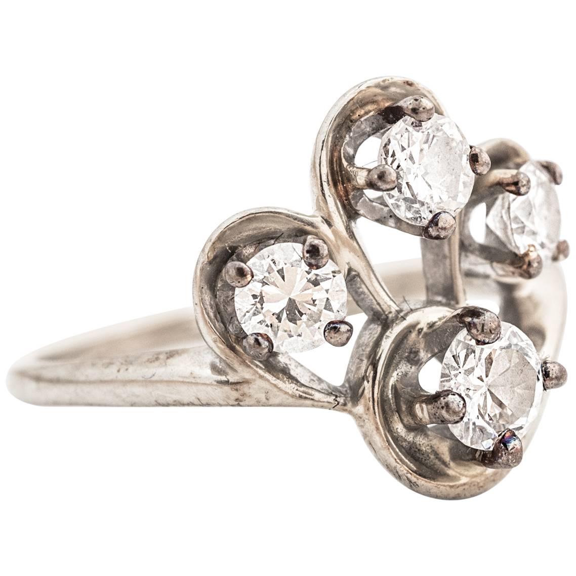 This retro ring features four diamonds cut in the Old European and Transitional Round fashion. Each diamond is entirely visible due to the elevated four-prong frames. The prongs are mounted on four swirled white gold sets, which give this ring a