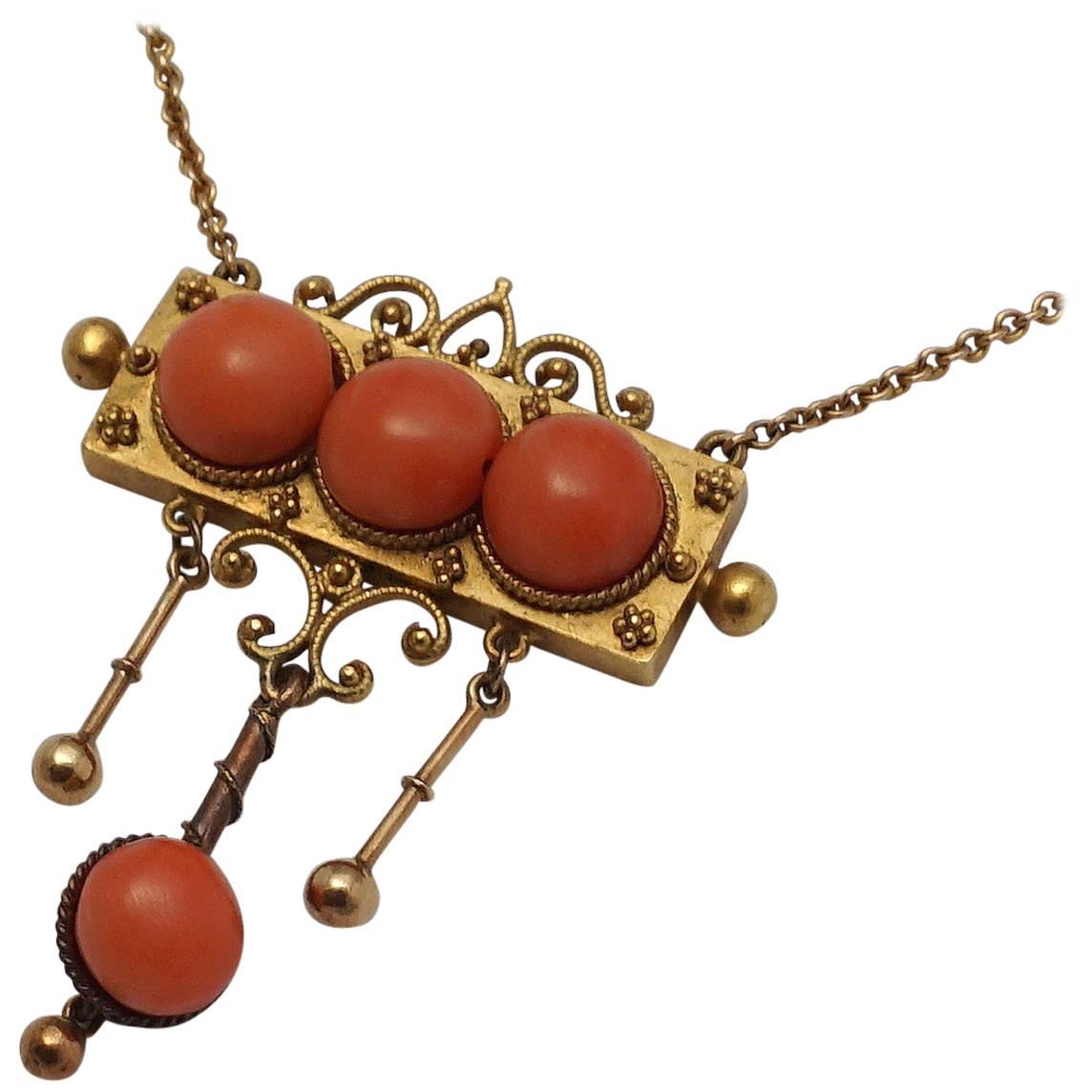 A beautiful victorian period coral, and 18 karat yellow gold necklace. Designed as a central plaque set with three cabochon cut coral. From this central plaque, are three dangling gold ornaments, one of which is also set with a coral cabochon.

In